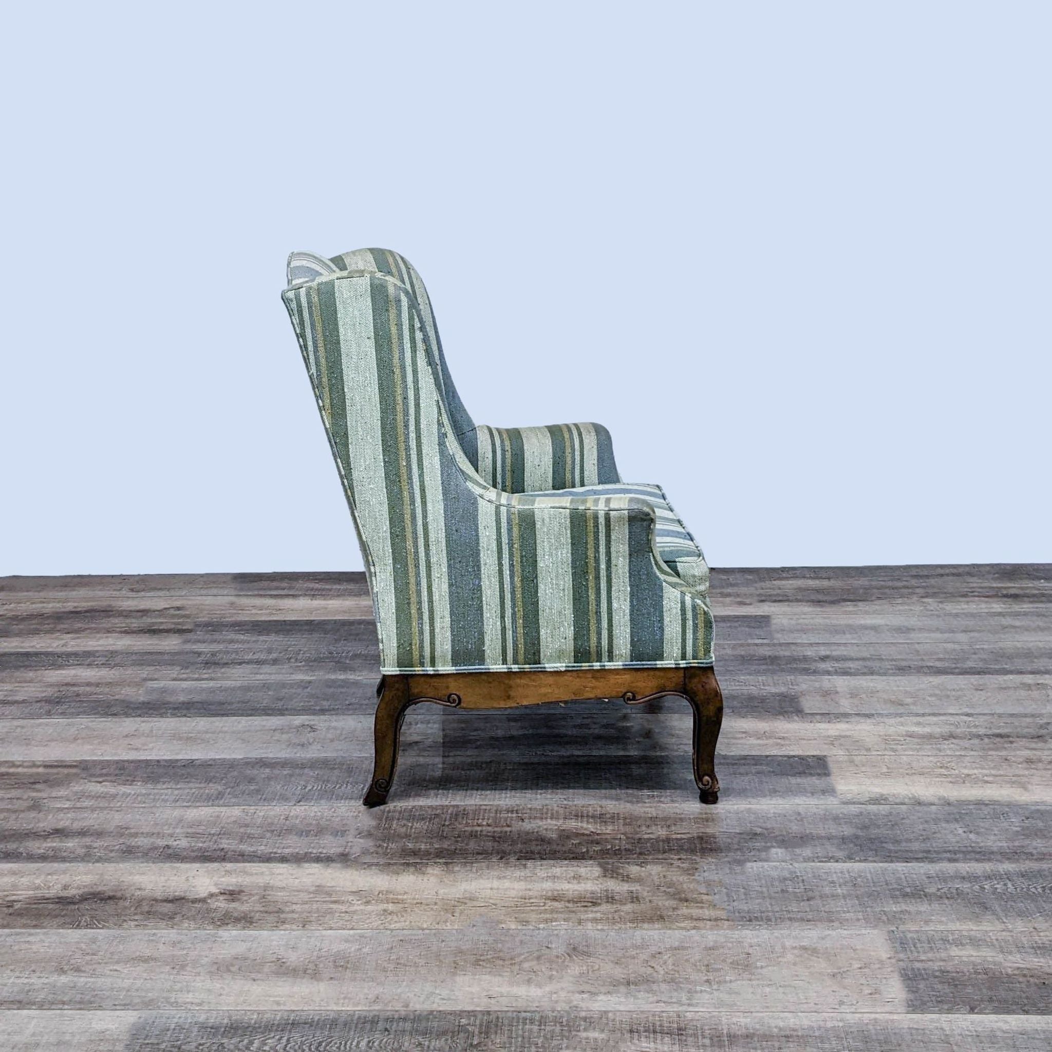 Side view of a striped upholstered Reperch wingback chair with curved wooden legs and detailed woodwork.