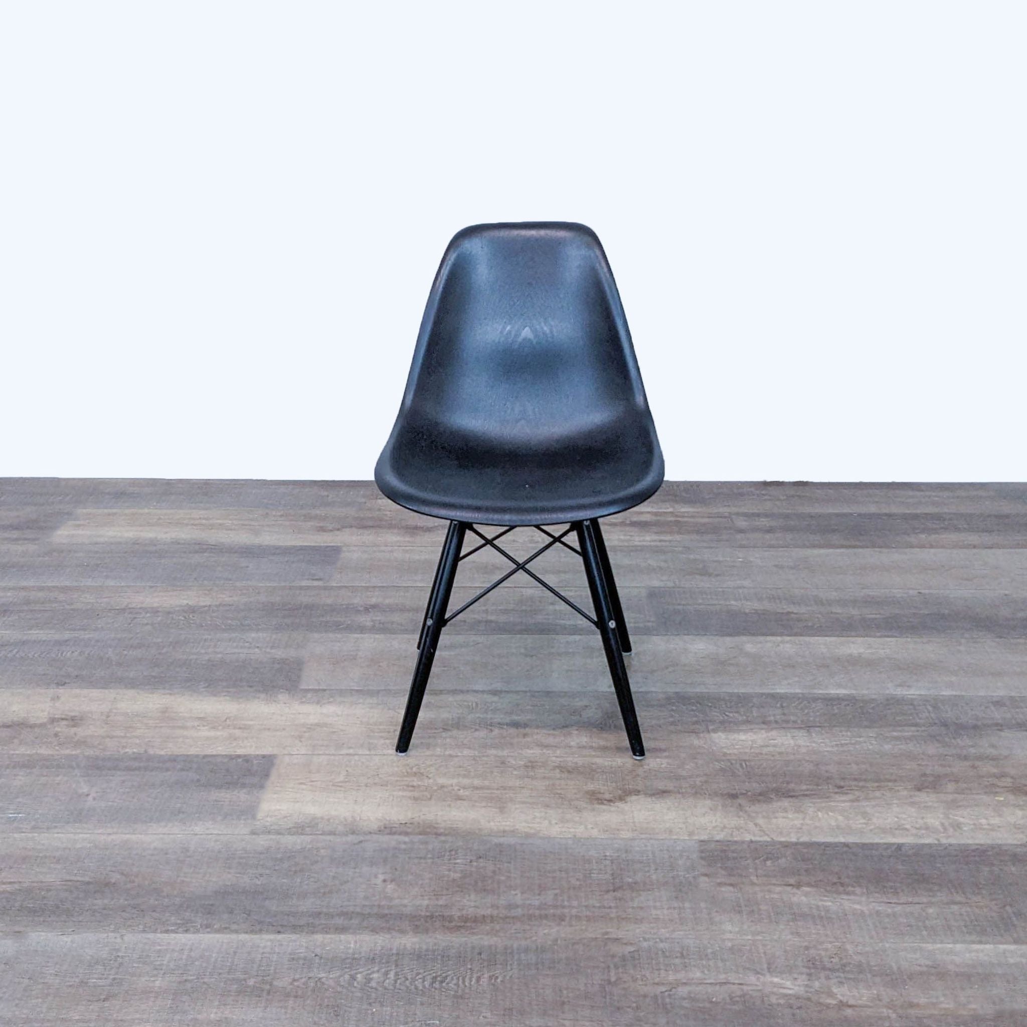 Black Reperch dining chair with contoured plastic seat and Eiffel-style walnut finish base, front view.