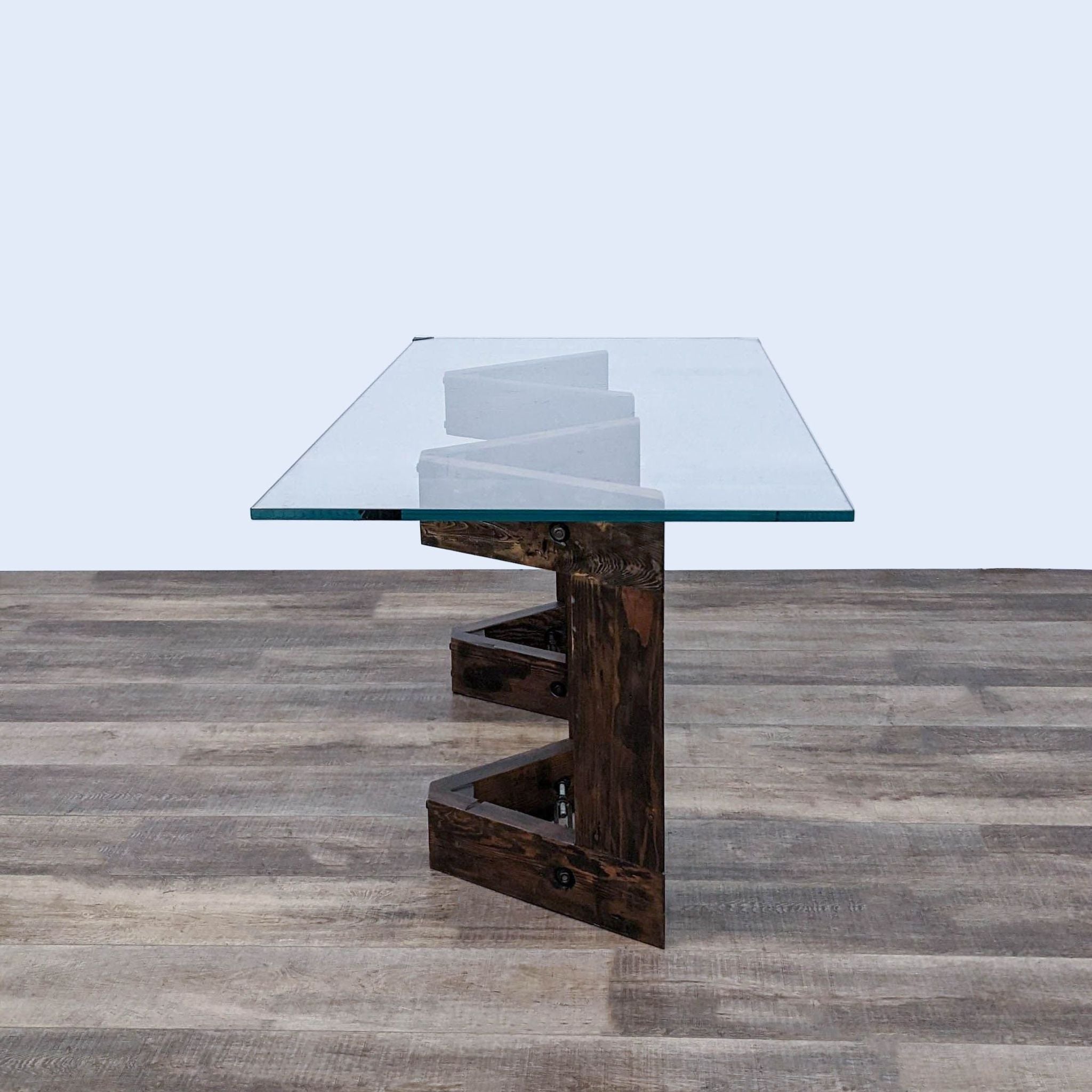 Thomas Bina designed coffee table featuring a V-shaped reclaimed wood base and a thick, clear tempered glass top with metal details.