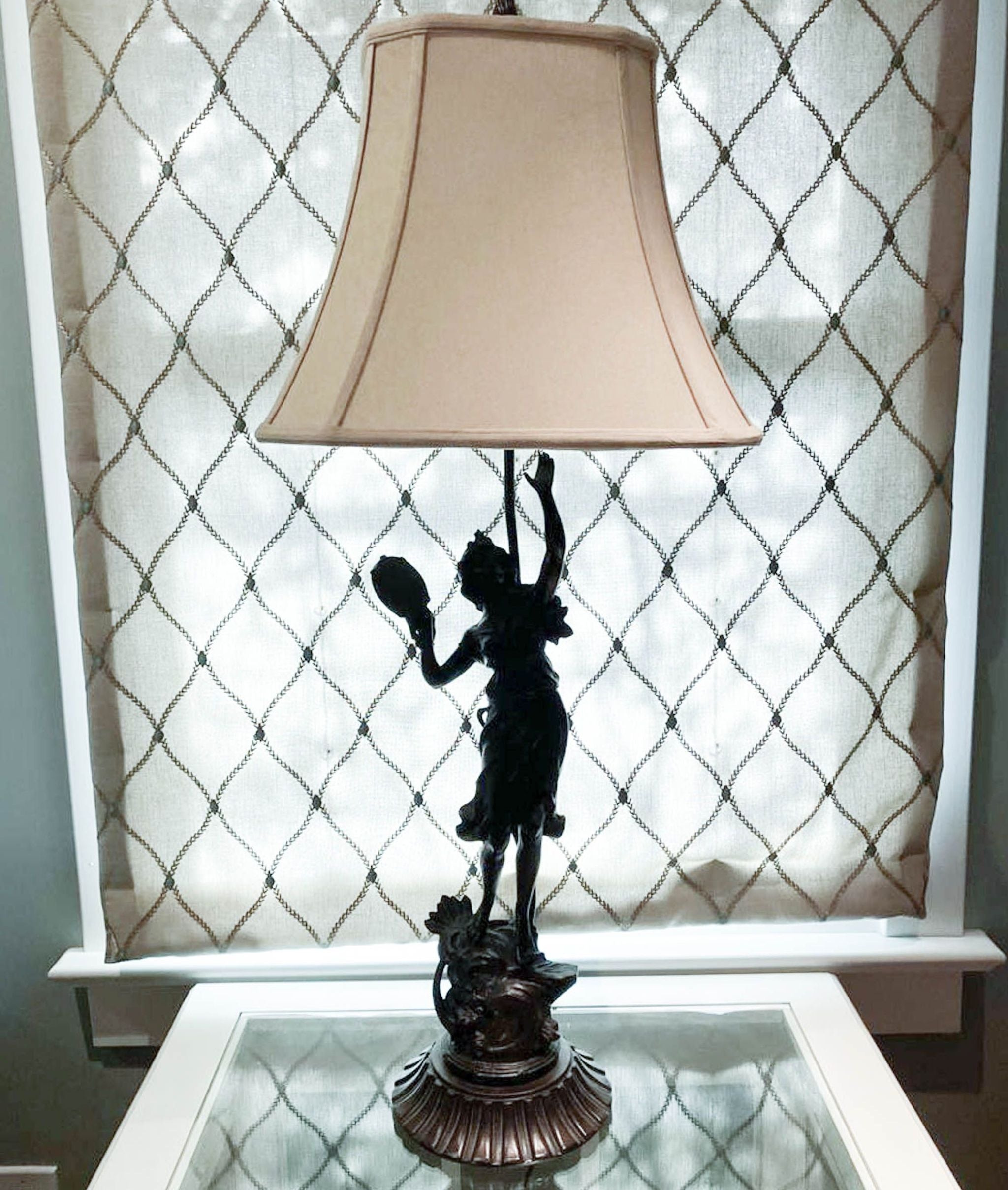 Alt text 1: Reperch brand table lamp featuring a bronze figurine of a woman raising a lampshade, set against a diamond-patterned curtain.