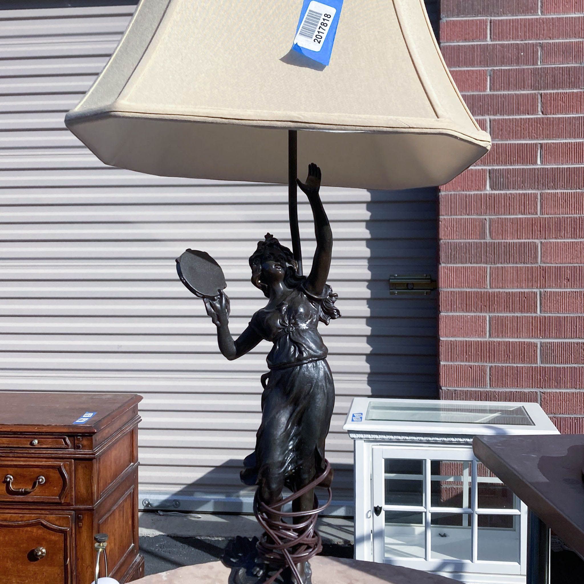 Alt text 2: Outdoor image of a Reperch lamp with a statuette base of a woman holding a mirror, a beige lampshade above her, and a price tag.