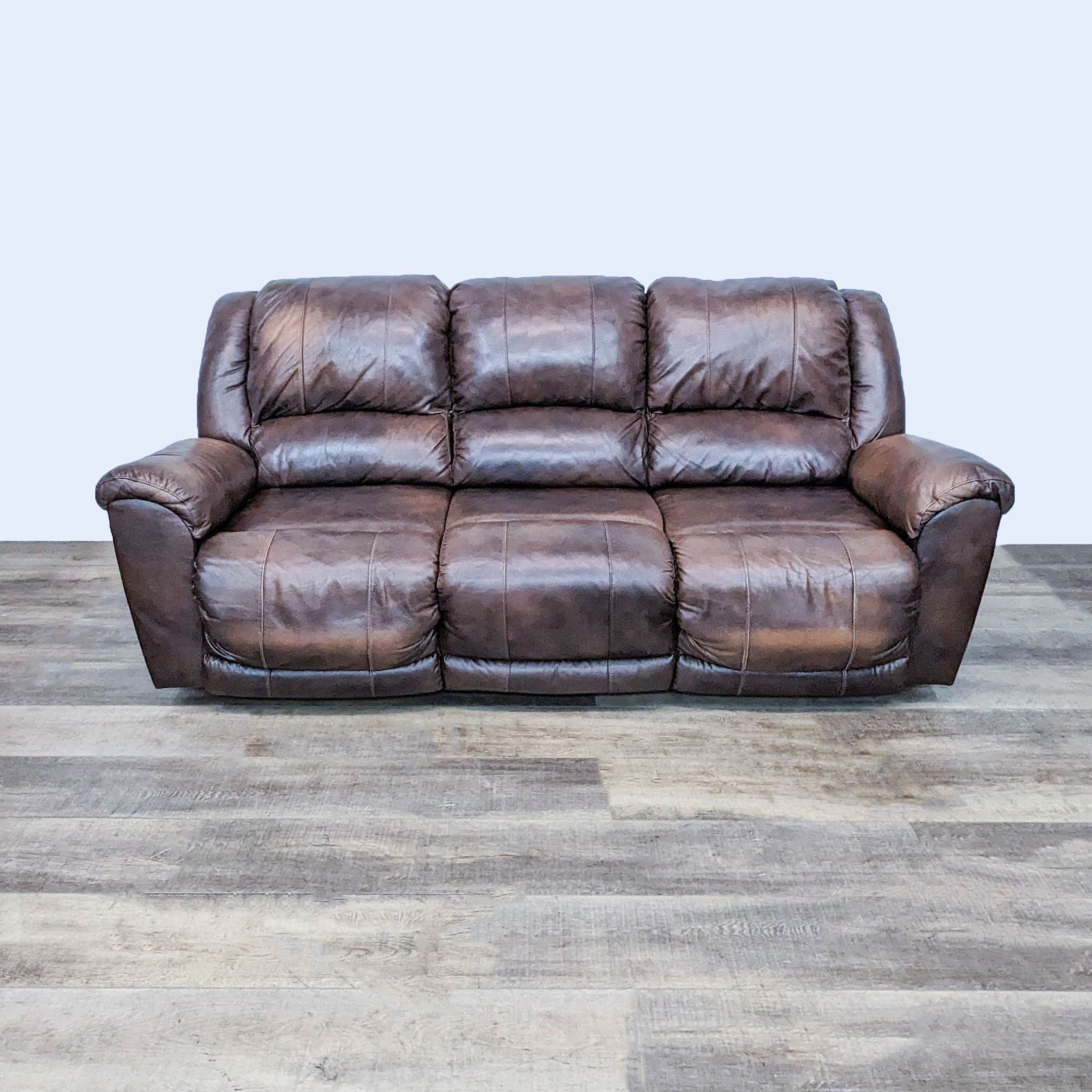 Ashley Furniture 3-seat brown leather recliner sofa with one seat extended, high backrest.