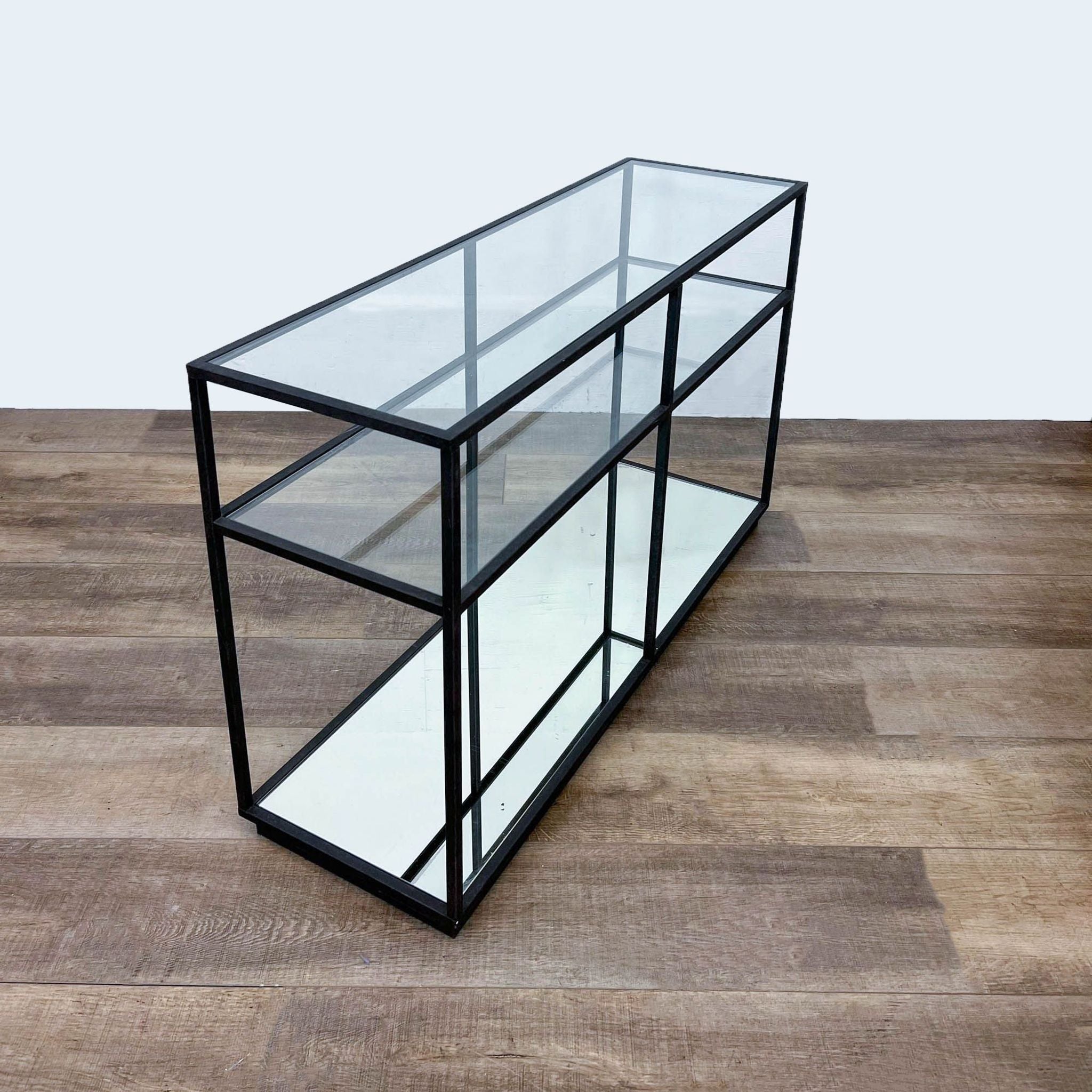 Elegant side table by Reperch with black metal structure and mirrored bottom shelf, angled view.