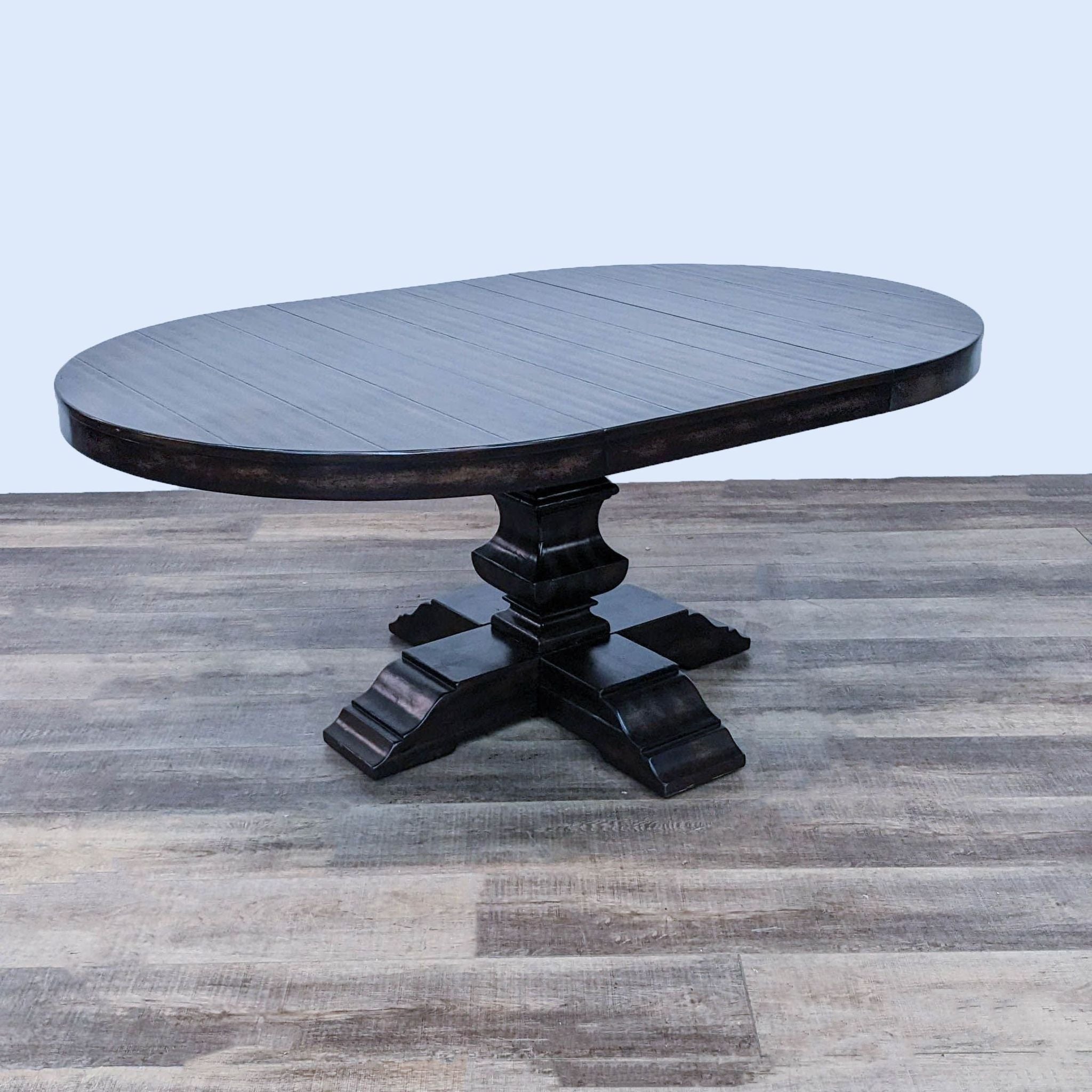 Round planked poplar dining table by Pottery Barn, finished in Alfresco Brown, with a baluster pedestal base on a wooden floor.