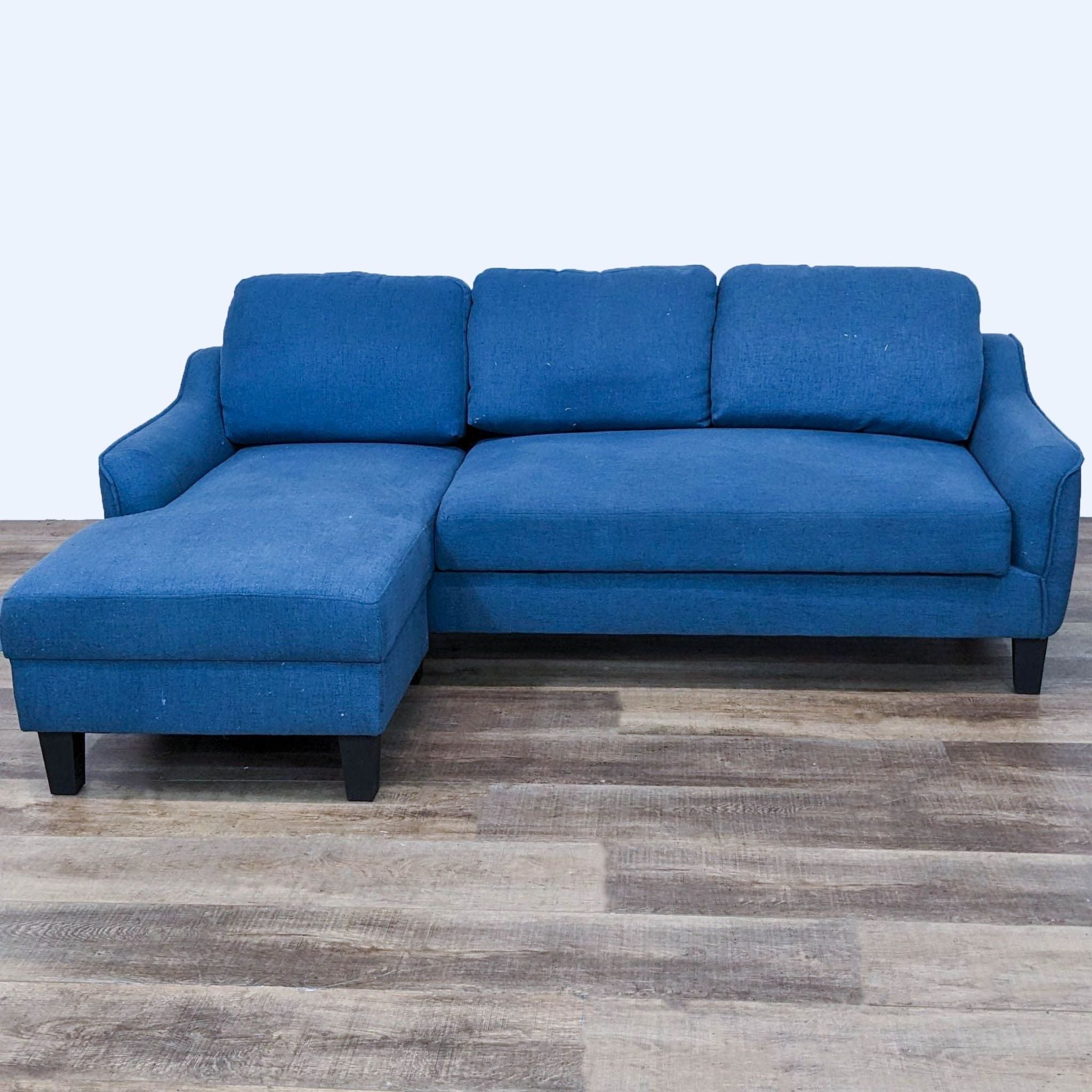 Reperch contemporary blue sectional with chaise and dark wood feet on a wooden floor.