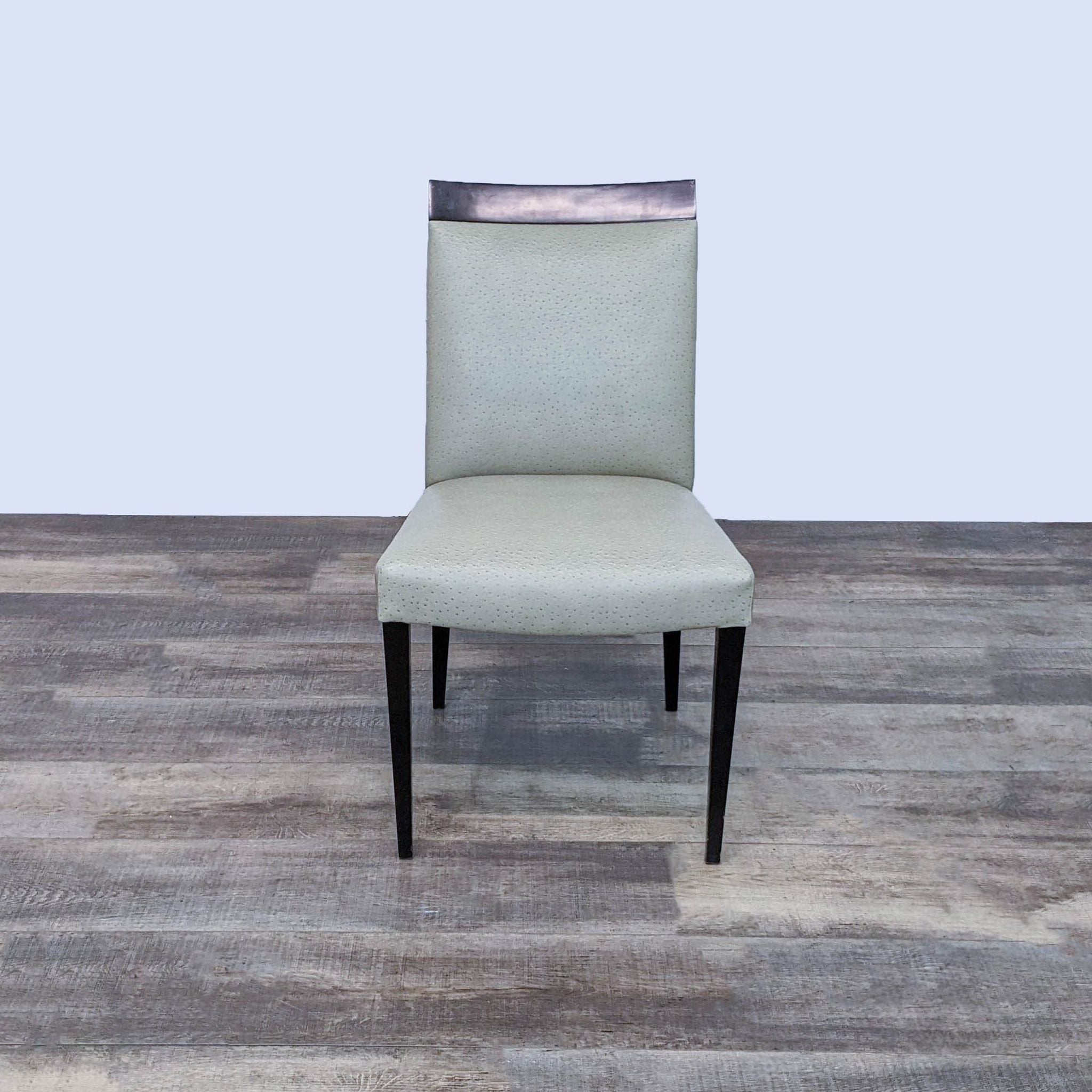 Reperch dining chair with tapered wood legs and a cushioned seat with brown leather top trim, on wood-style flooring.