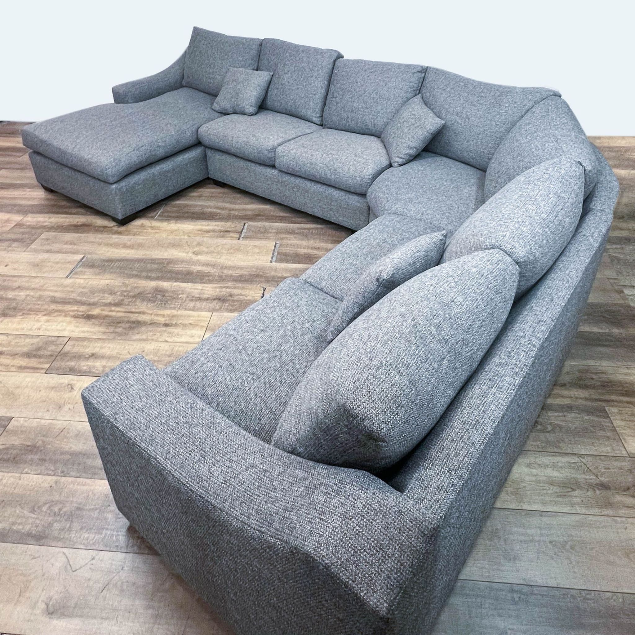 Gray Reperch sectional couch with plush cushions and dark base, displayed in a spacious setting.