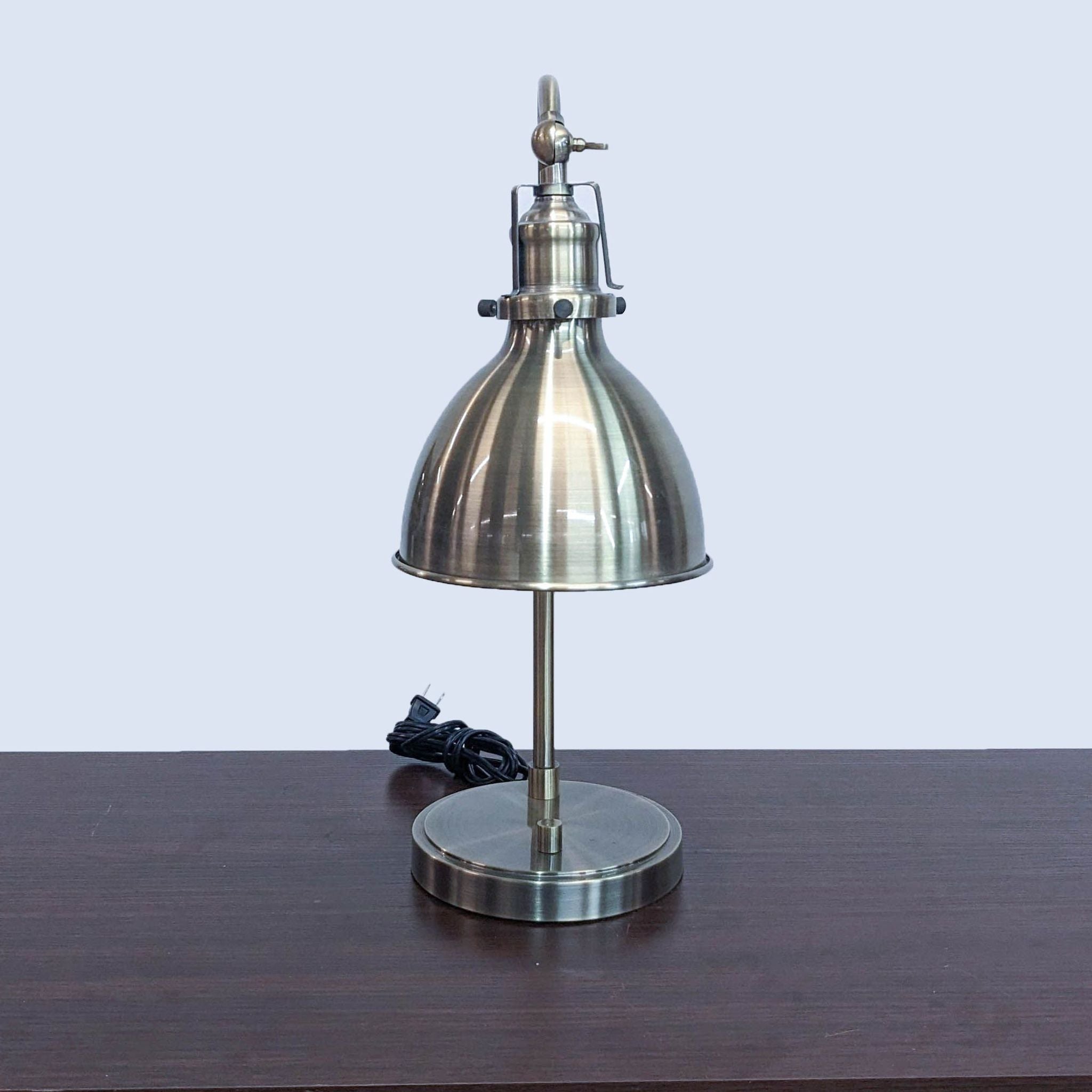 Brushed metal Intertek desk lamp with a vintage design, bell-shaped shade, and power cord, placed on wood surface.