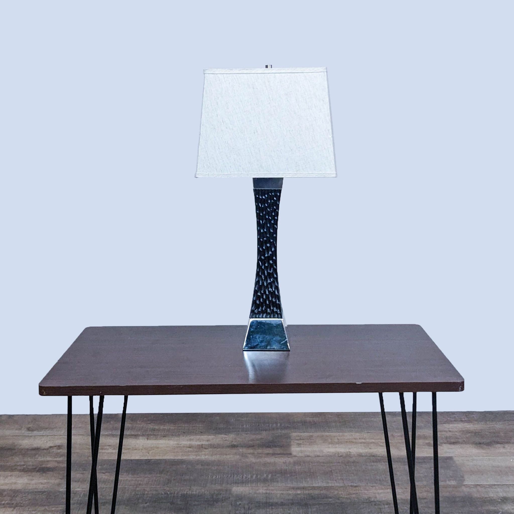 Reperch branded table lamp with a textured base and square white shade on a wooden table against a gray backdrop.