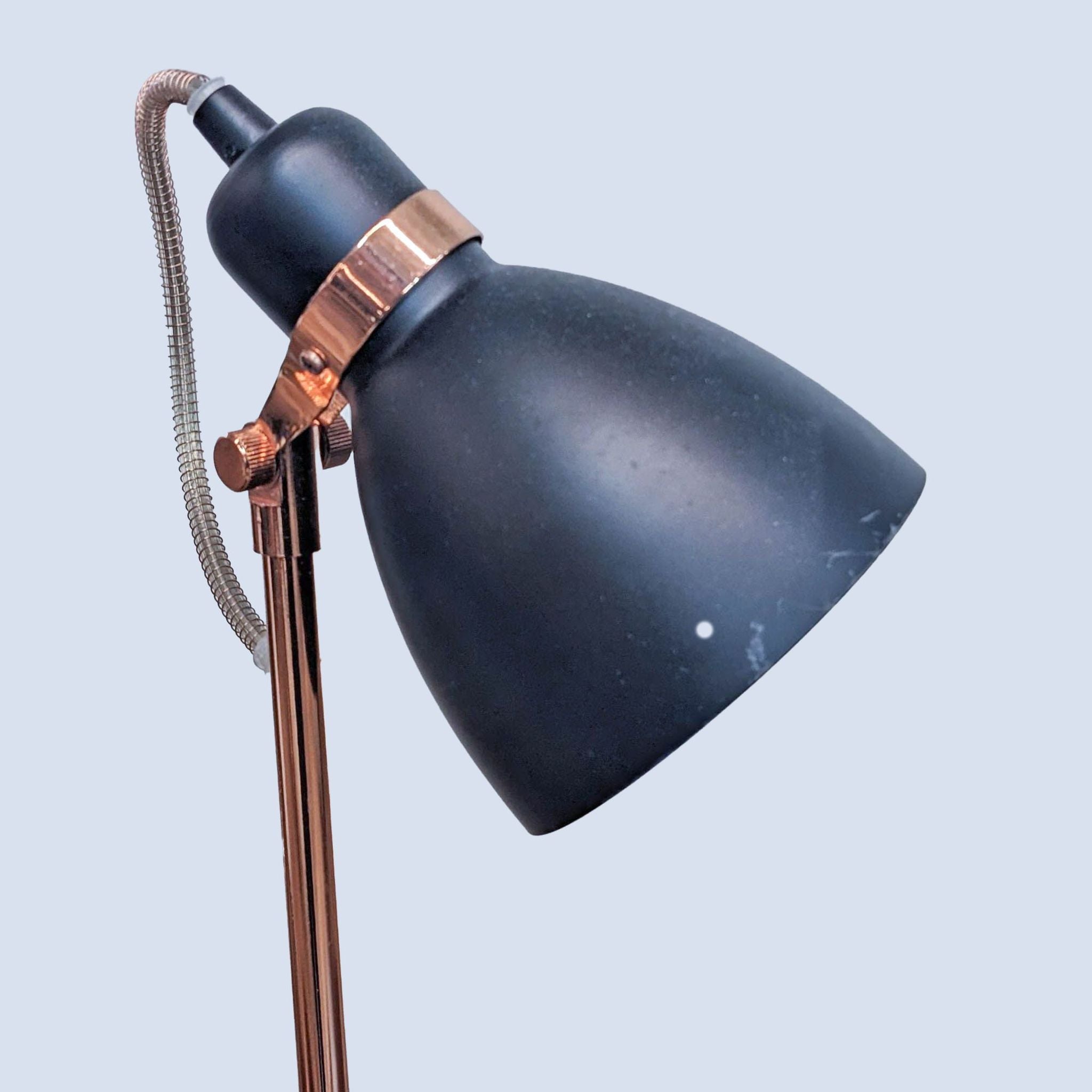 Close-up of a Reperch desk lamp featuring a matte black shade, copper detailing, and a flexible neck on an isolated background.