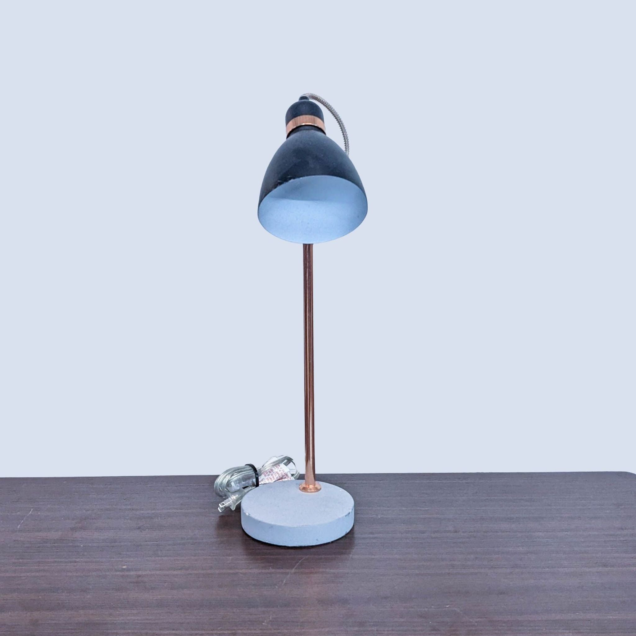 Reperch branded table lamp with blue shade and copper post on wooden surface.
