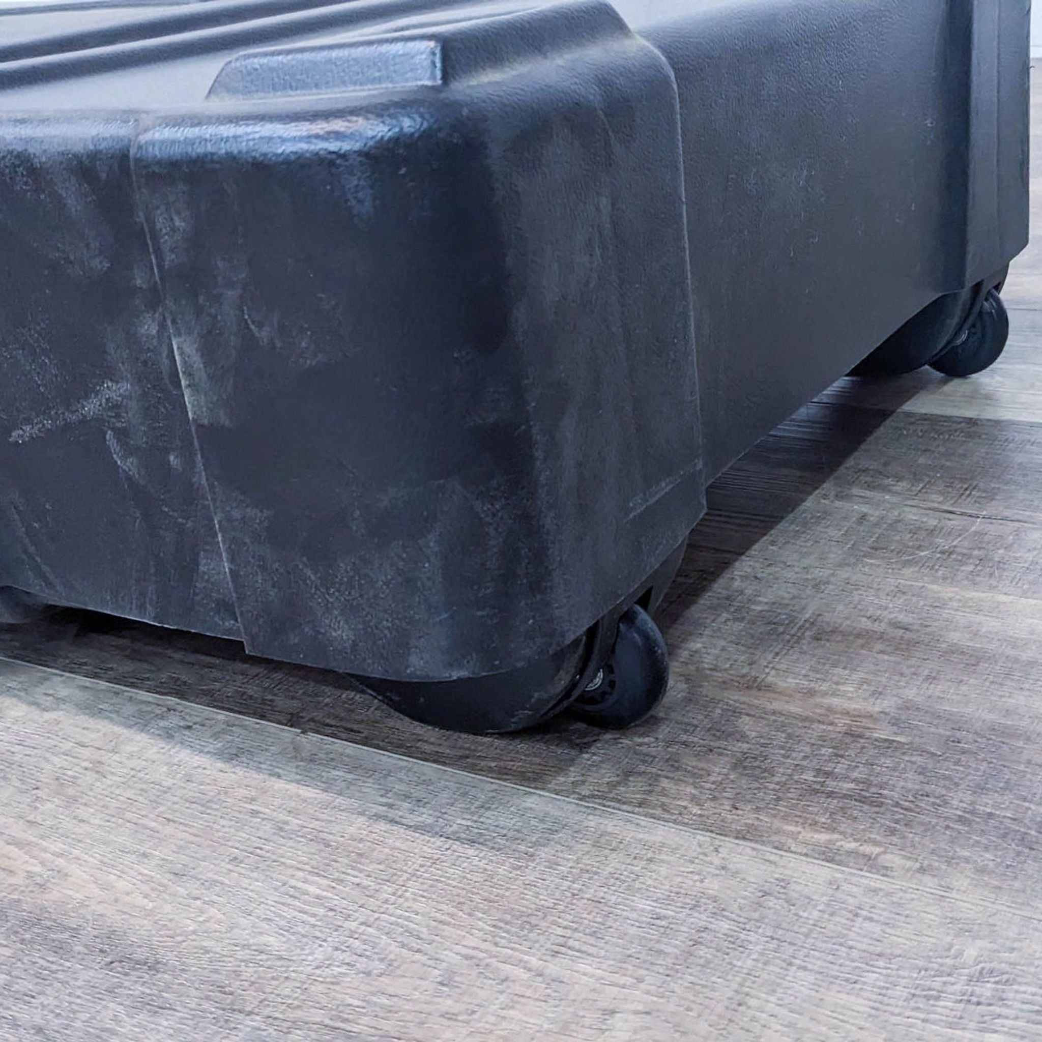 Close-up of the bottom of a Mod Displays rolling hard case, emphasizing the wheels for portability on a wooden floor.