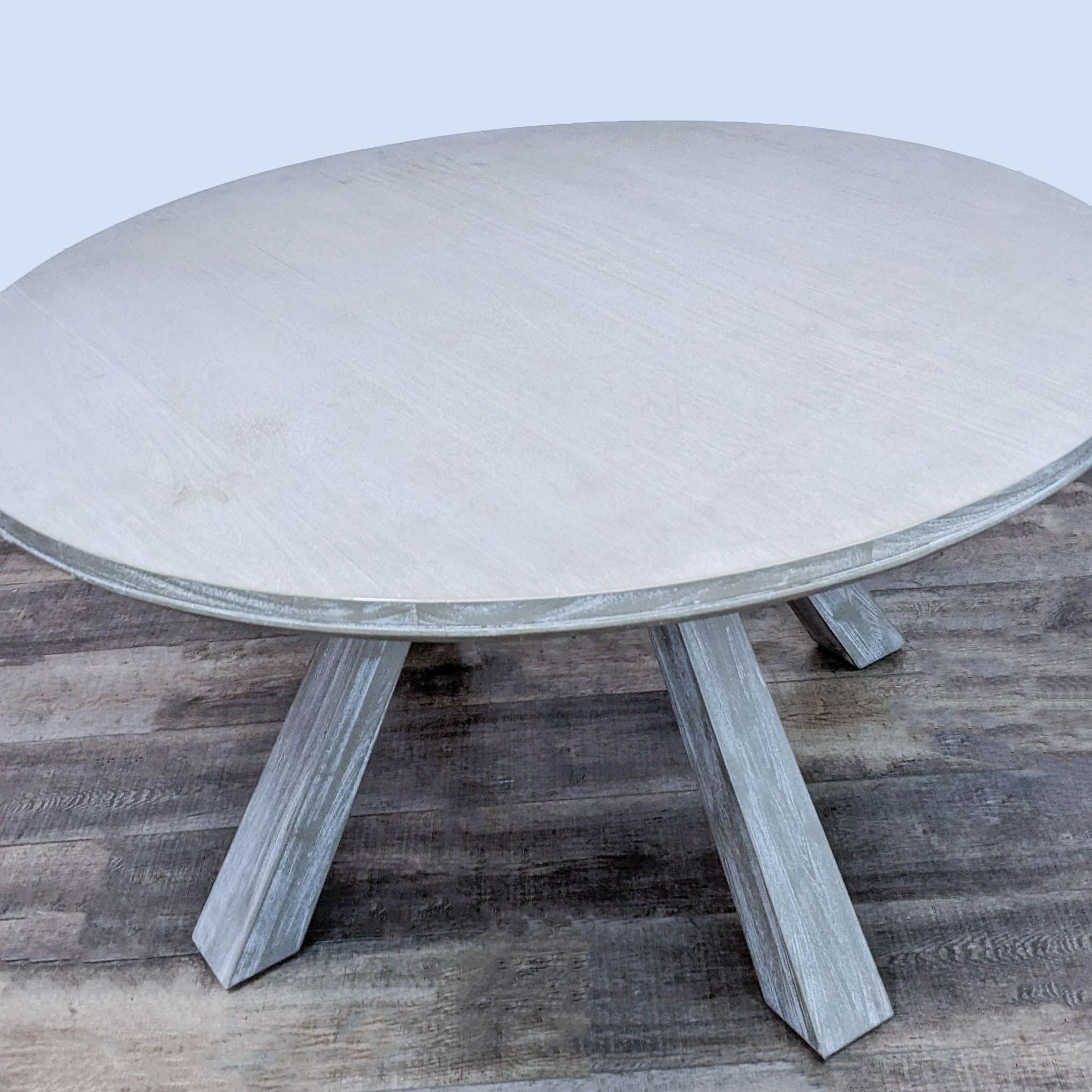 Solid acacia wood dining table, round top, coastal feel, by Zuo Modern, with sun-dried bleached finish.