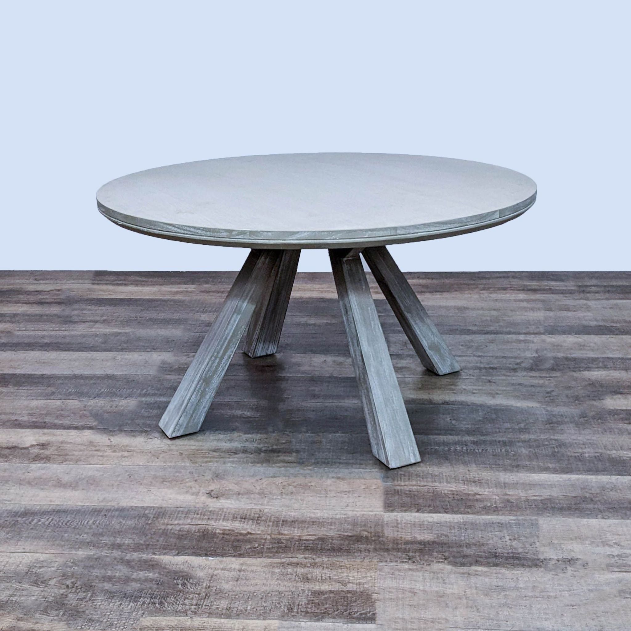 Round Beaumont dining table by Zuo Modern with bleached sun-dried finish and flared legs.