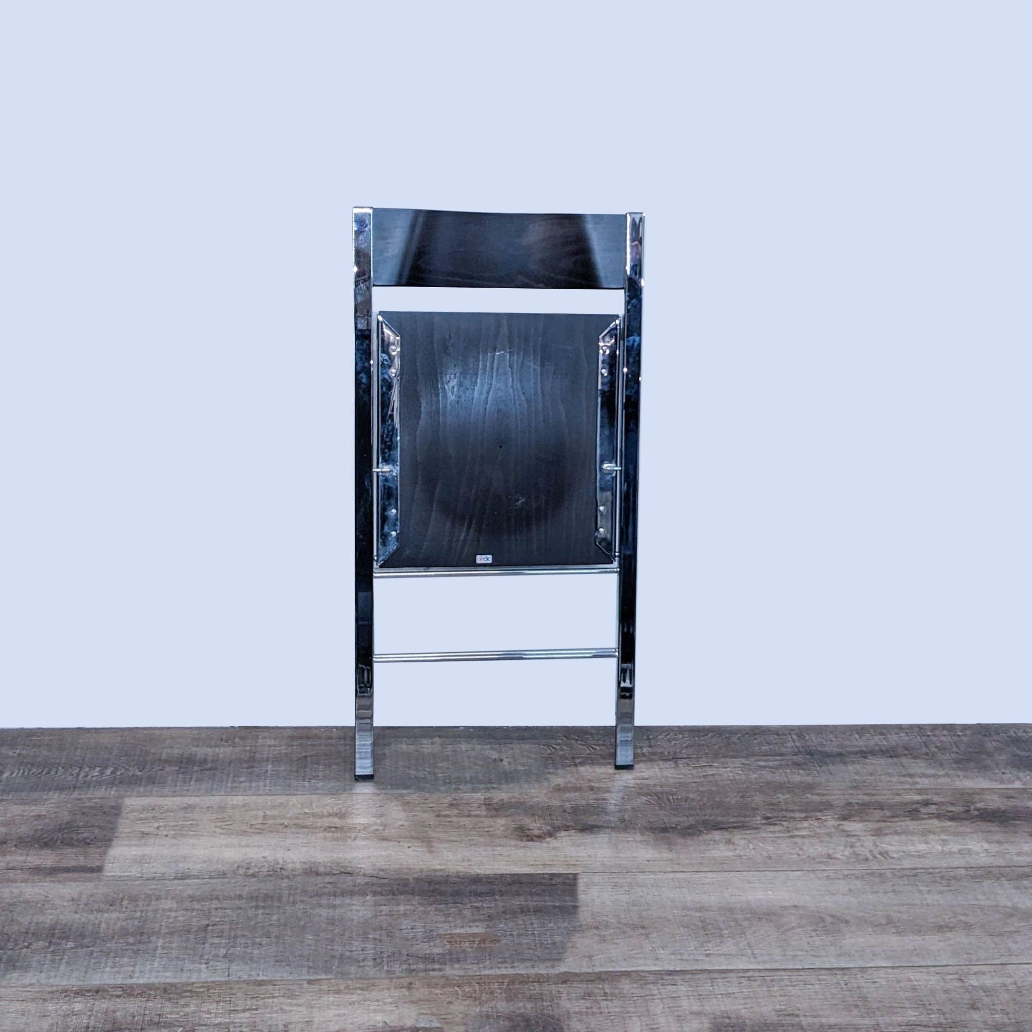 Alt text 2: Front view of Area DeClic Pocket chair by Resource Furniture, showcasing the modern style chrome frame and wood seat, positioned on a wooden floor.