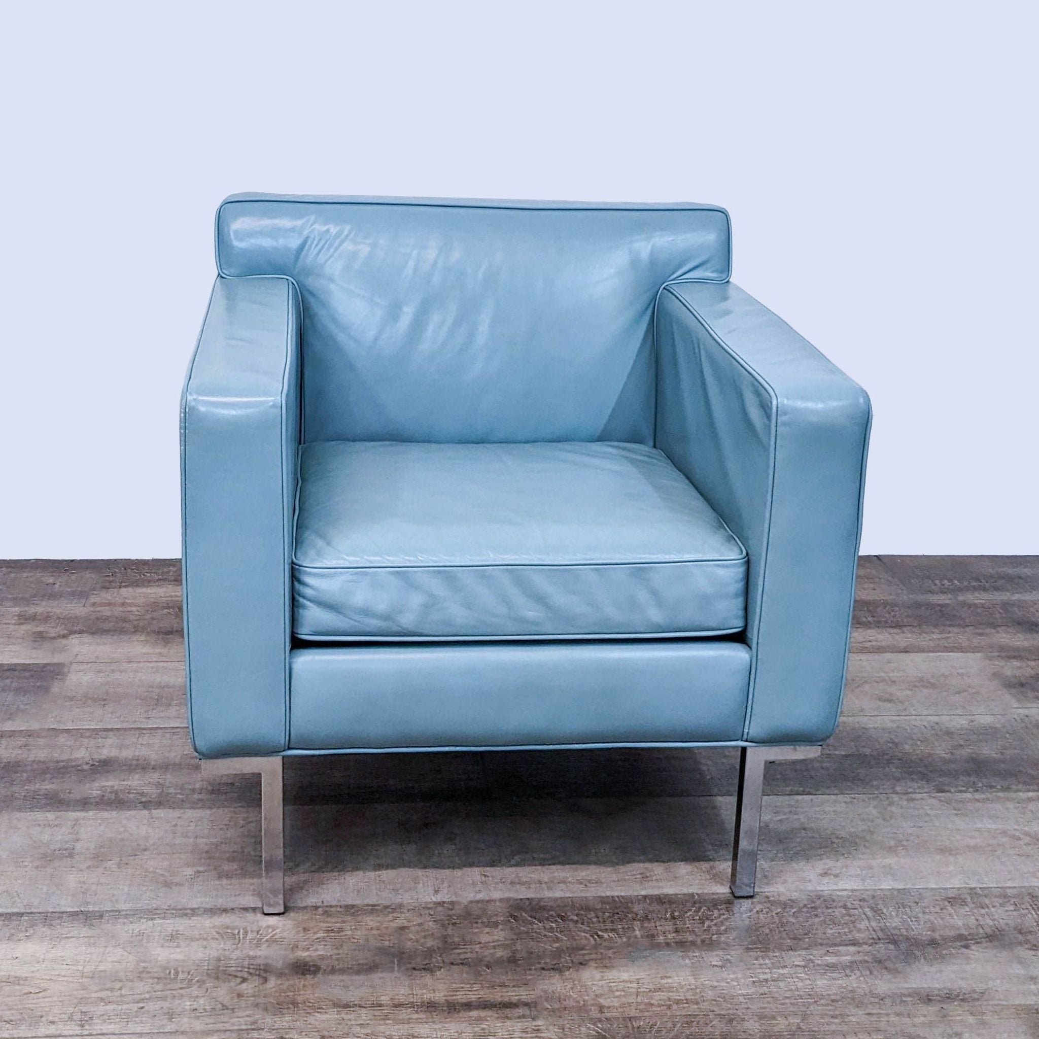 Design Within Reach Theatre armchair with light blue leather upholstery, an angled backrest, and elevated armrests on a chromed steel base.