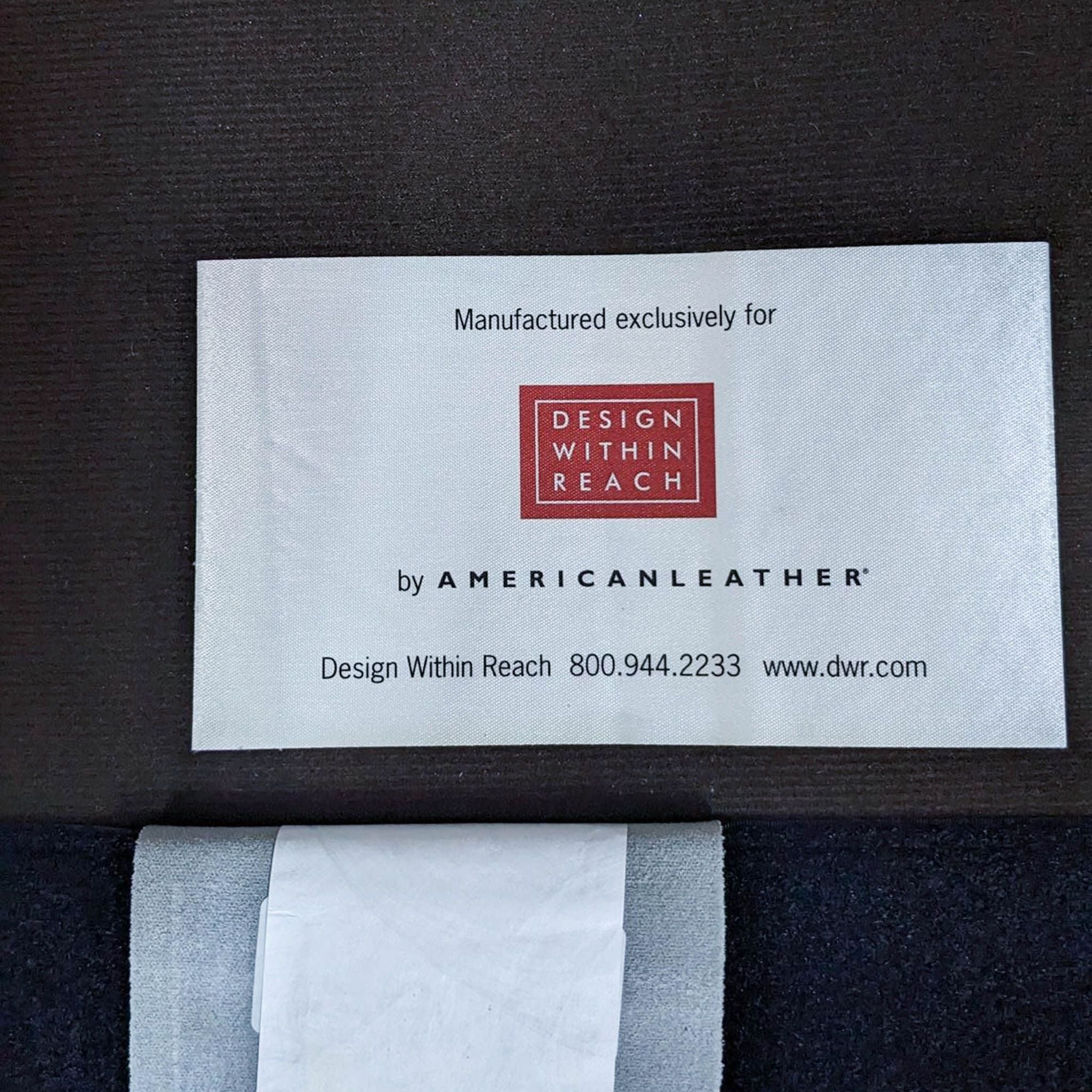 Alt: Design Within Reach label by American Leather on a leather piece, indicating exclusive manufacturing for the brand.