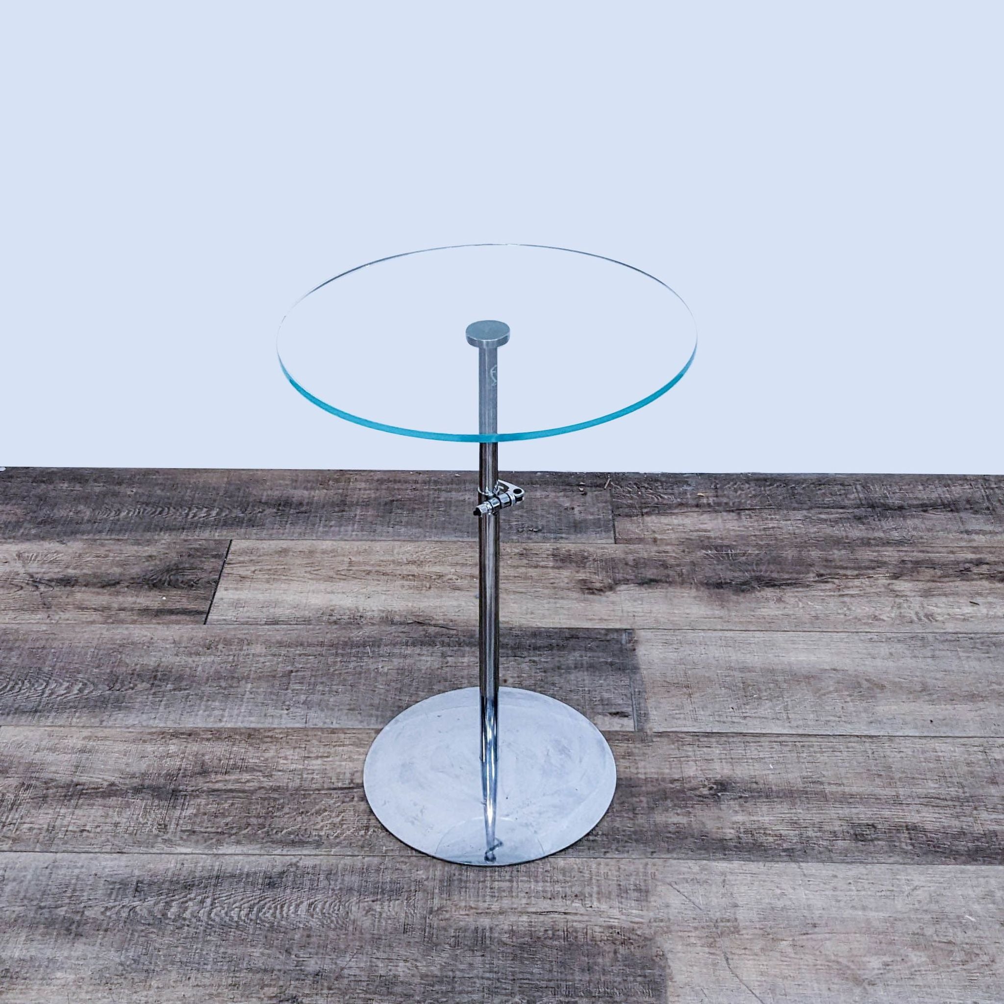 Elevated view of a Crate & Barrel round glass-topped side table with sleek chrome stand, showcasing brand label.