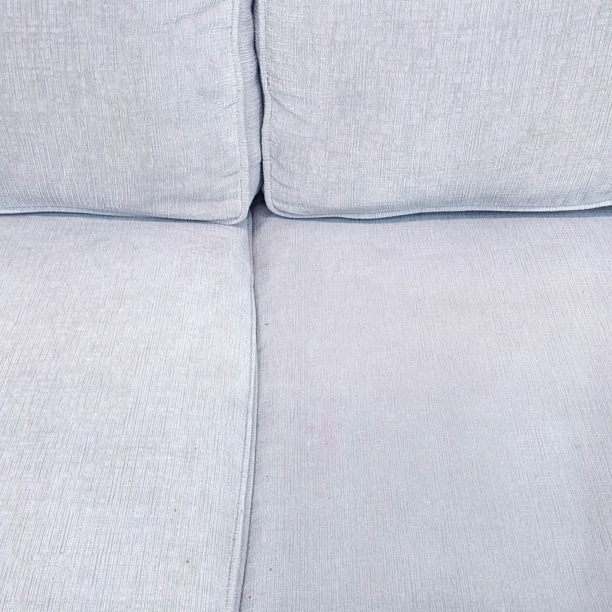 Close-up of beige upholstered sofa detailing track arms and T back cushions by Living Spaces.