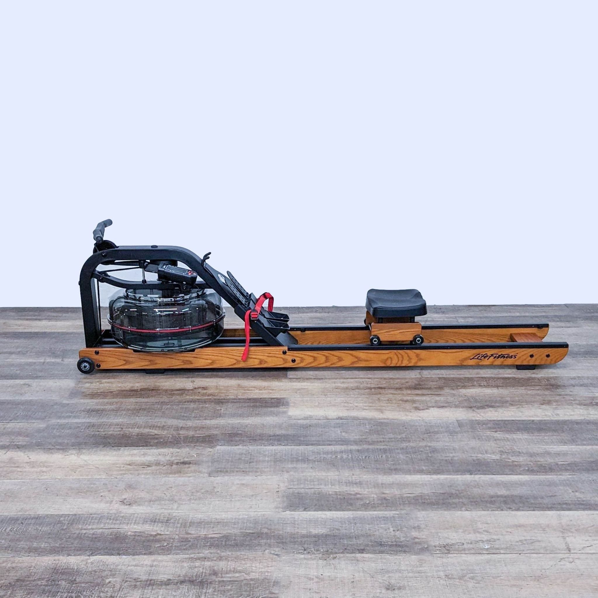 Life Fitness wooden indoor rowing machine on a grey floor, side view.