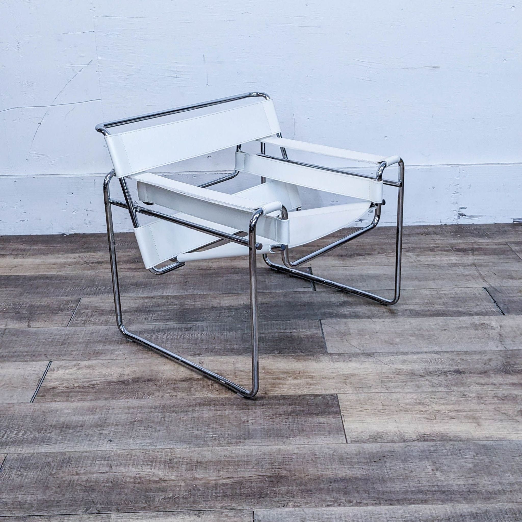 Knoll lounge chair with white leather and chrome frame, angled view on wooden floor against a white wall.