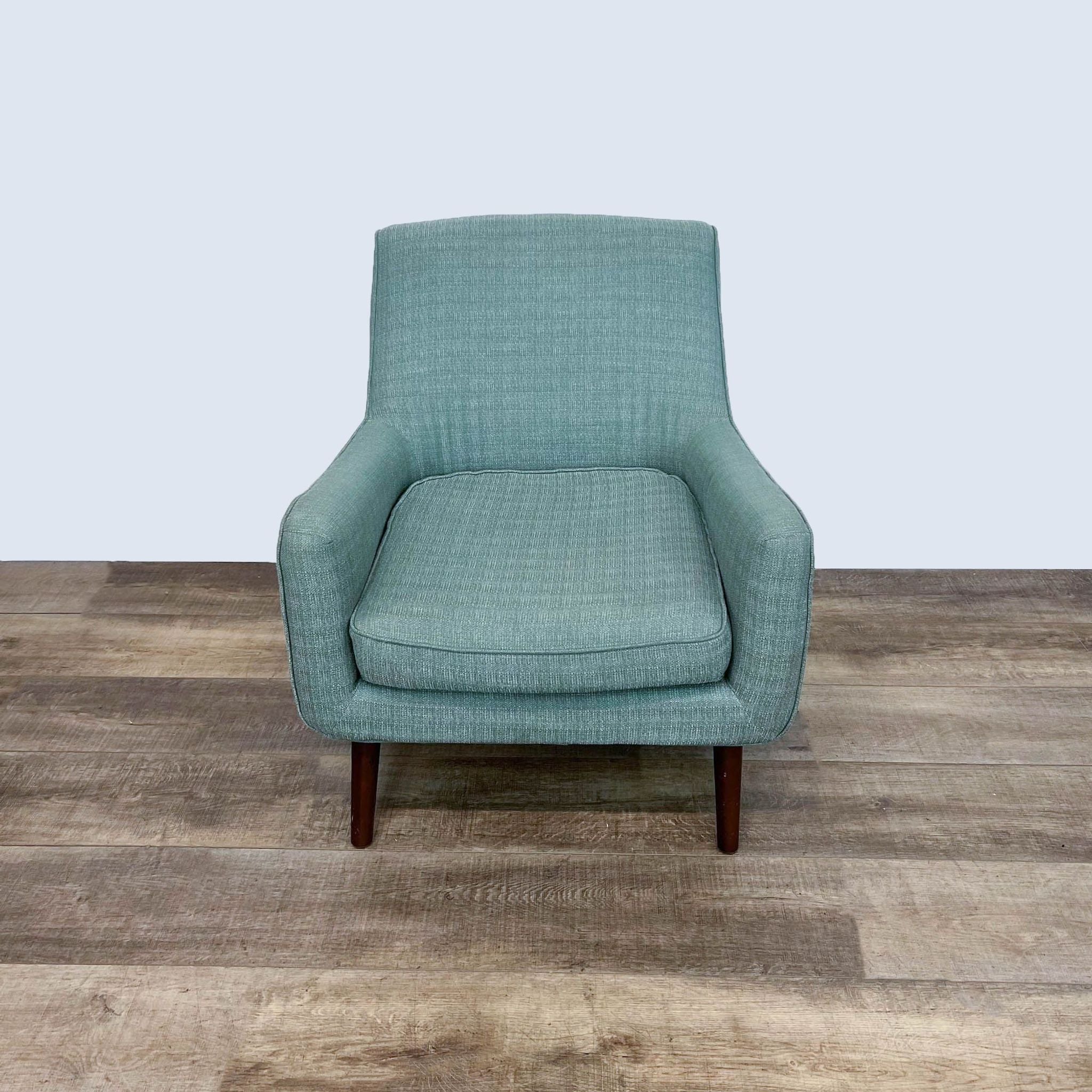 Madison Park's Liam chair in a mid-century style with angled legs and green upholstery, shown from front view on a wooden floor.