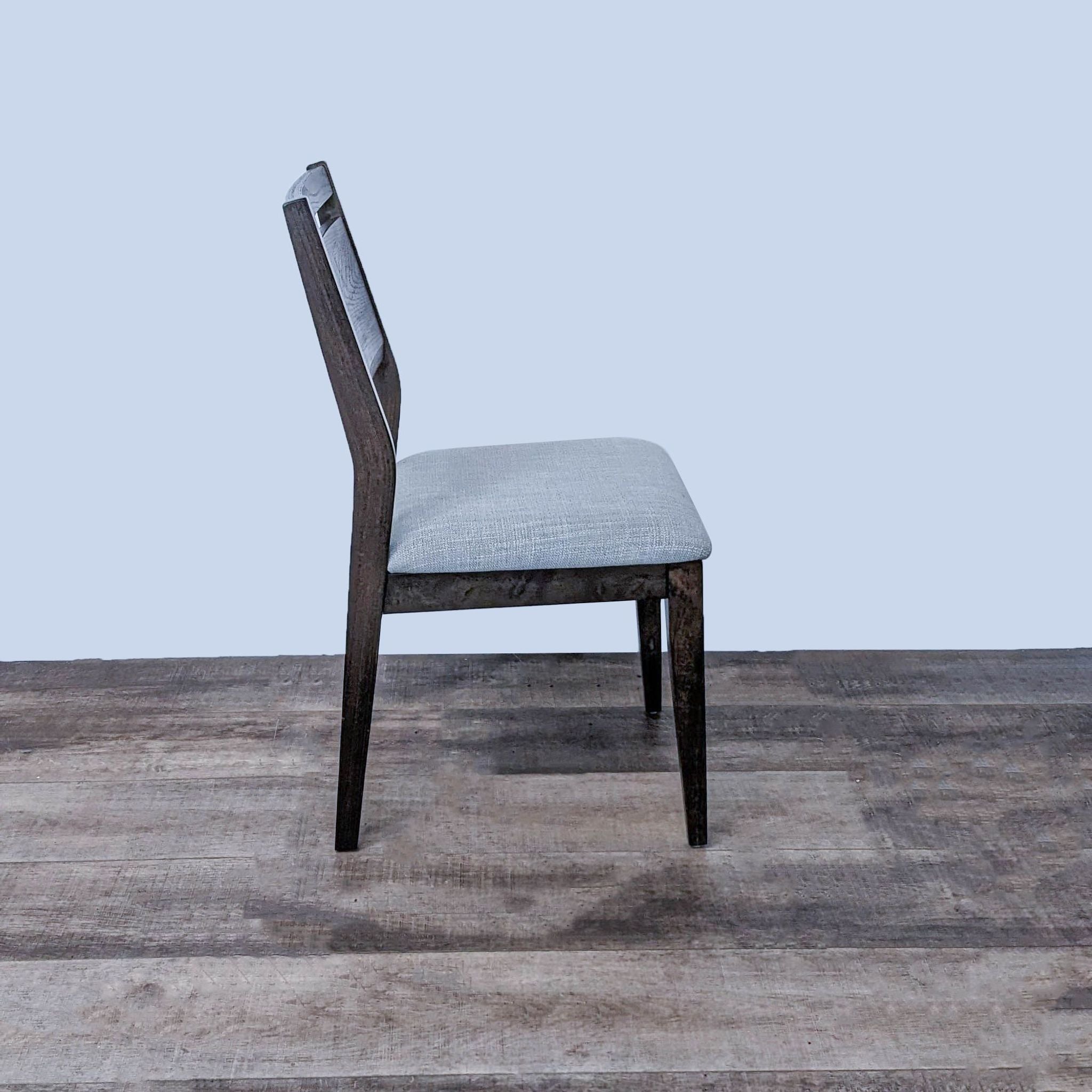 Side view of Reperch dark-finished wood dining chair with cushioned seat in a room setting.