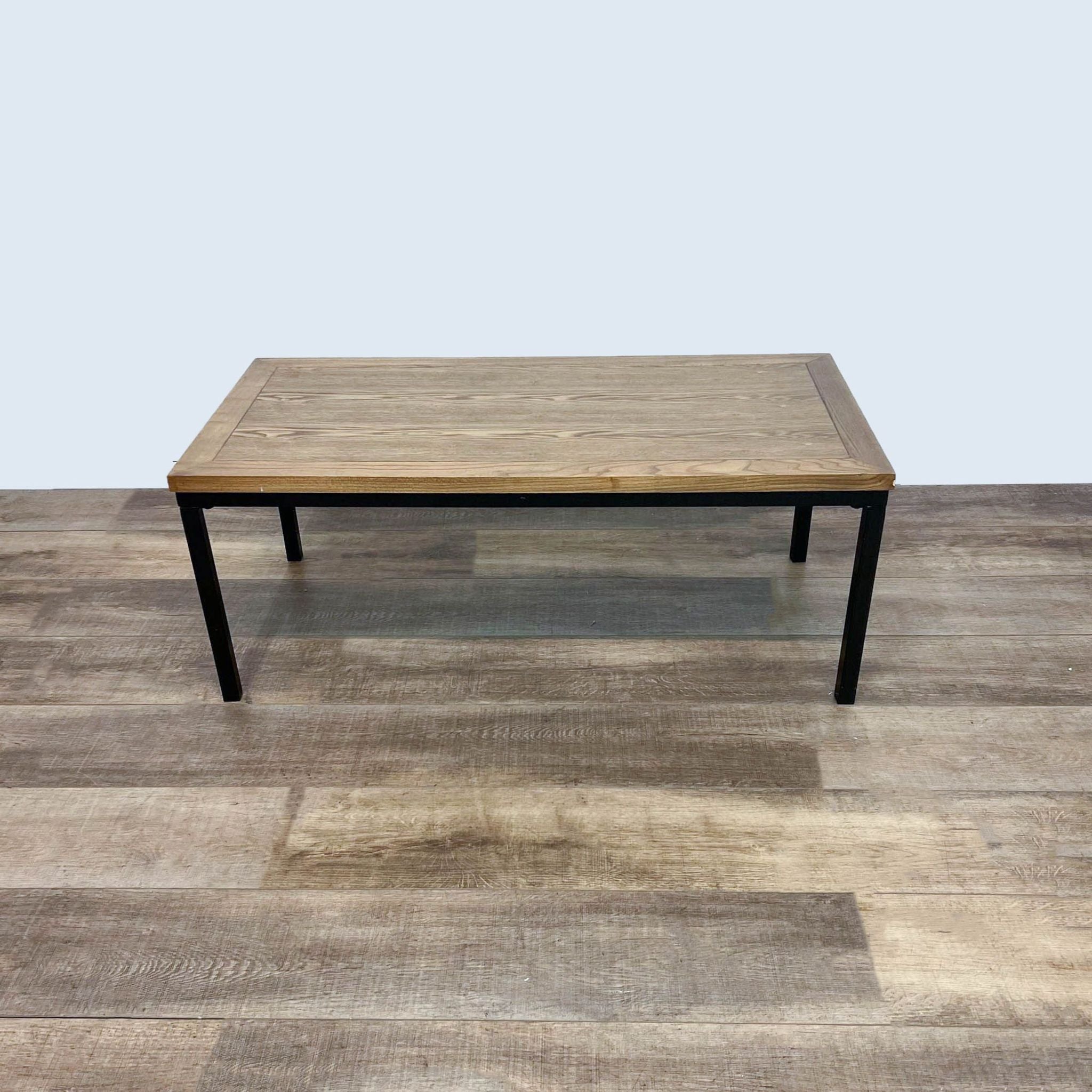Reperch brand coffee table with a natural wood top and black metal legs on a wooden floor.