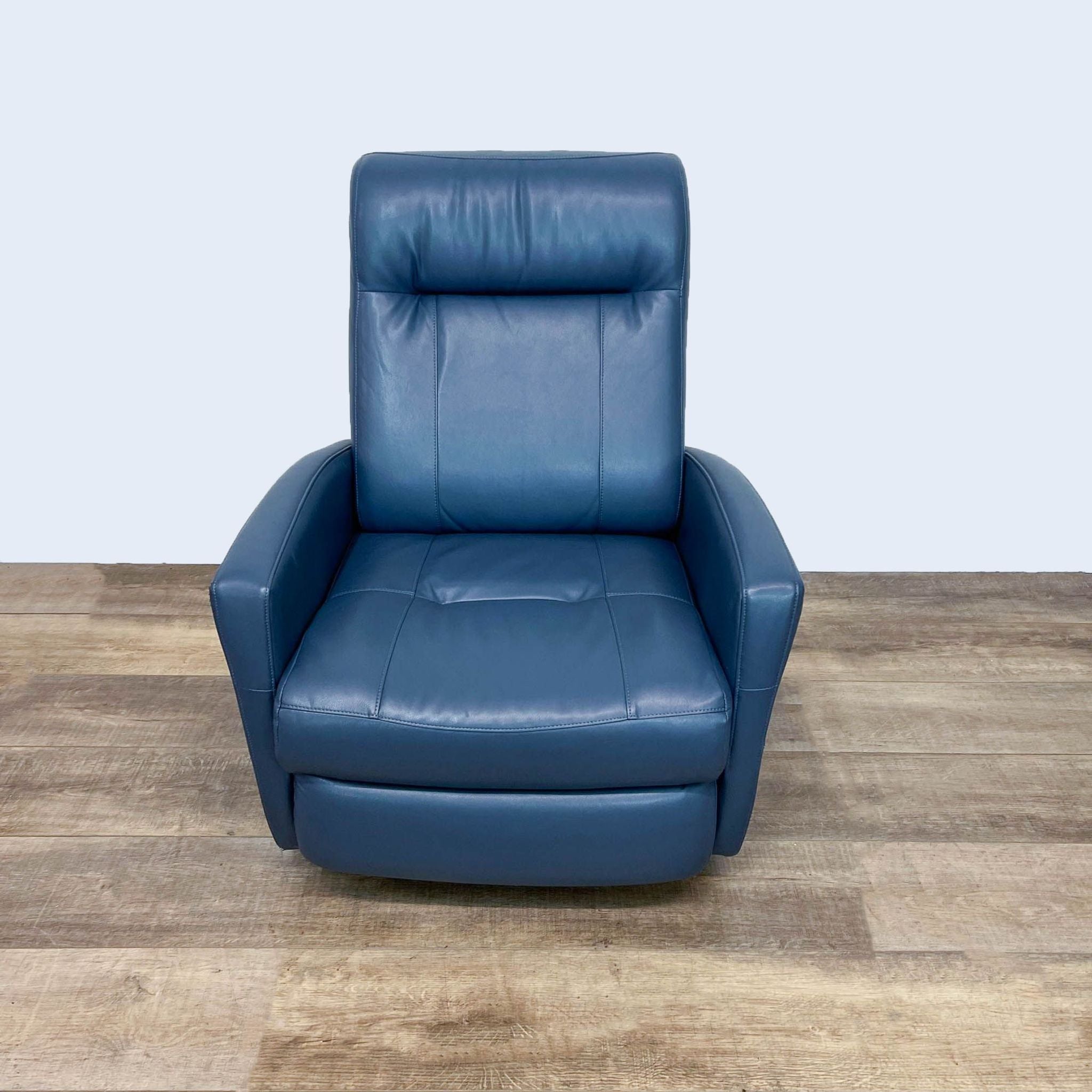 Reperch brand leather recliner with tufting and swivel base in upright position against a wooden floor and white backdrop.