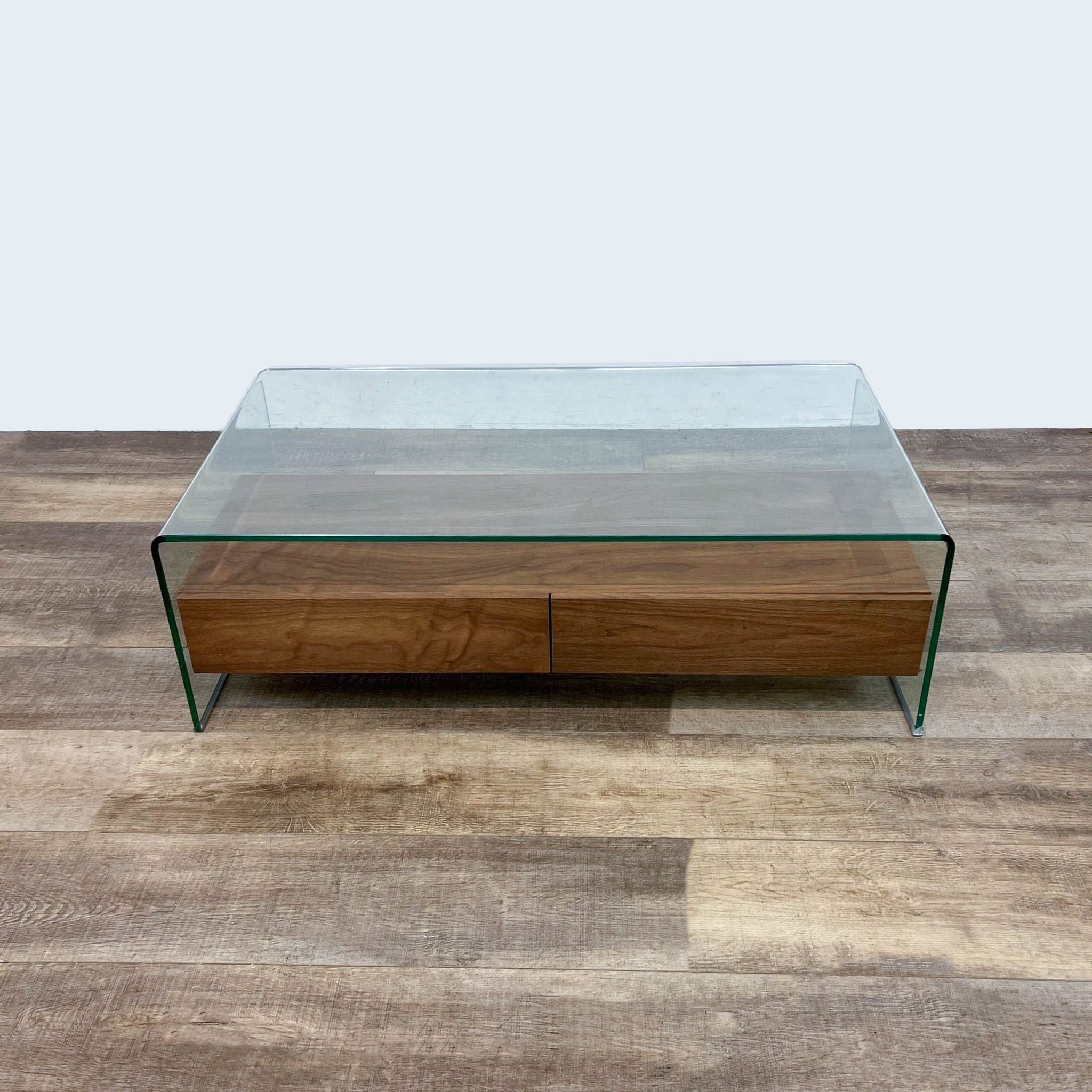 1. Zuo Modern coffee table with a clear glass waterfall design and two closed walnut drawers on a wooden floor.