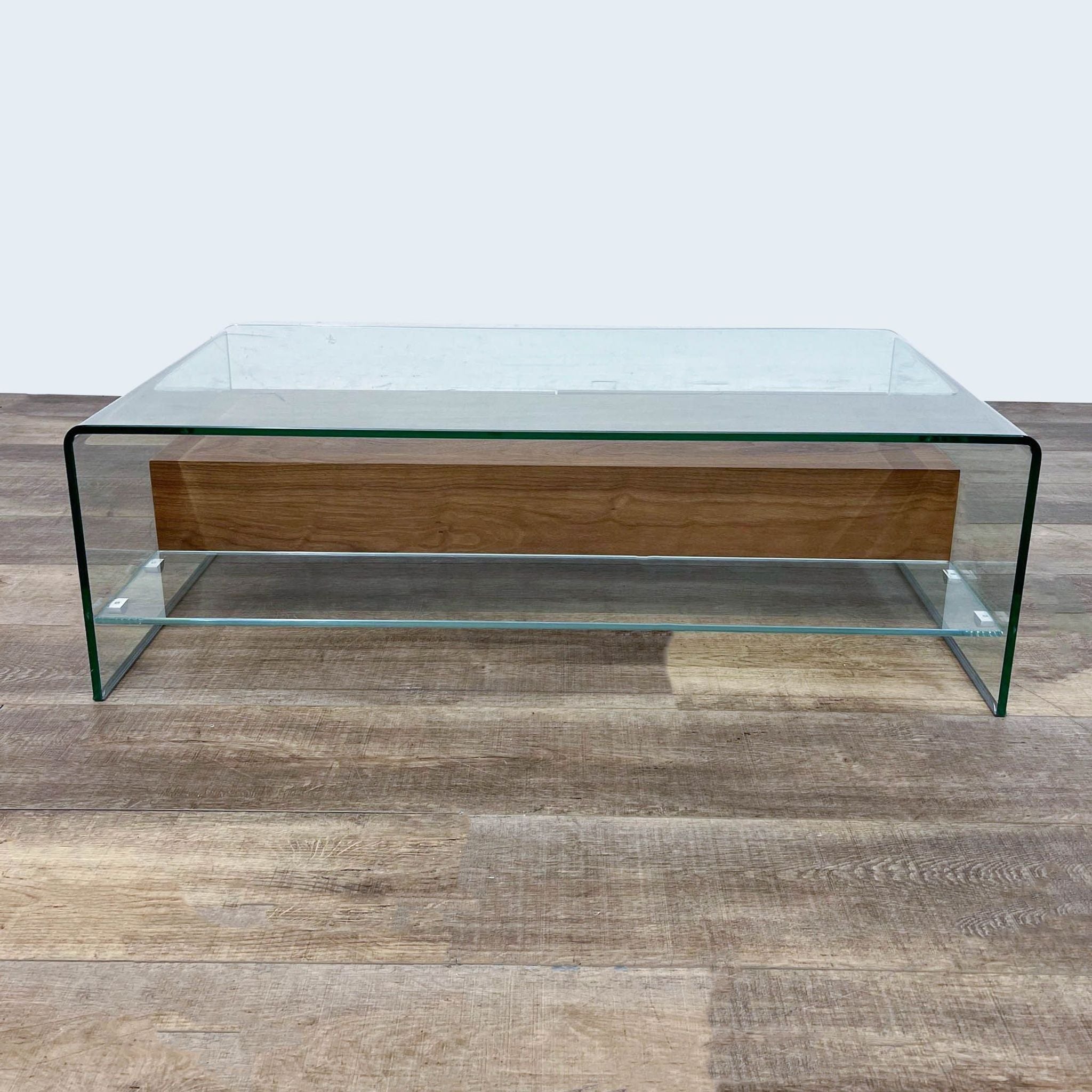 Zuo Modern coffee table featuring a glass waterfall design with two integrated walnut drawers, displayed on a wooden floor.