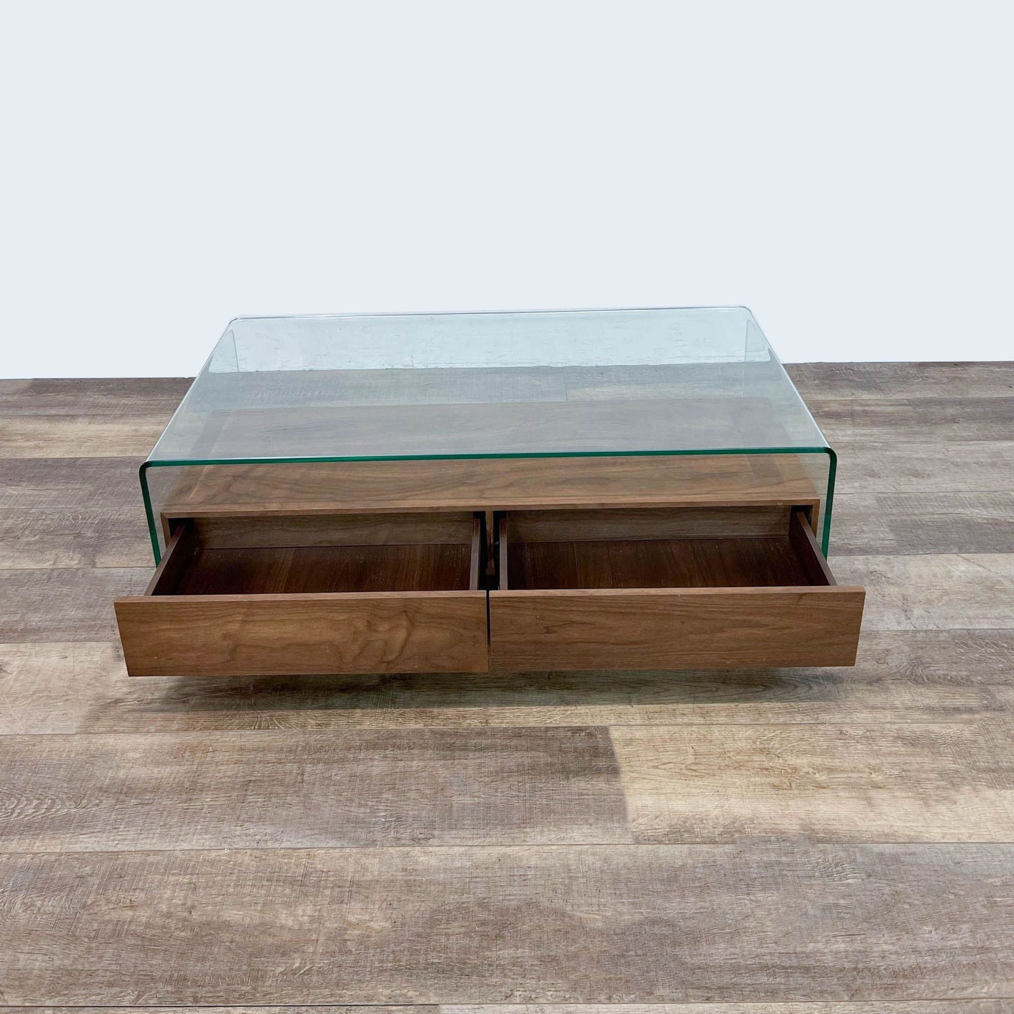 2. Modern glass coffee table by Zuo with open walnut drawers showcasing storage space, placed on a wooden floor.