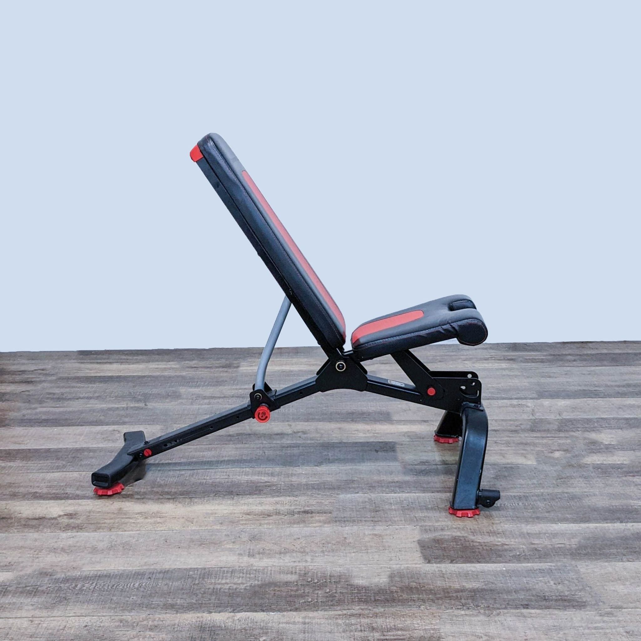Bowflex adjustable workout bench positioned on a wooden floor with a grey wall background.