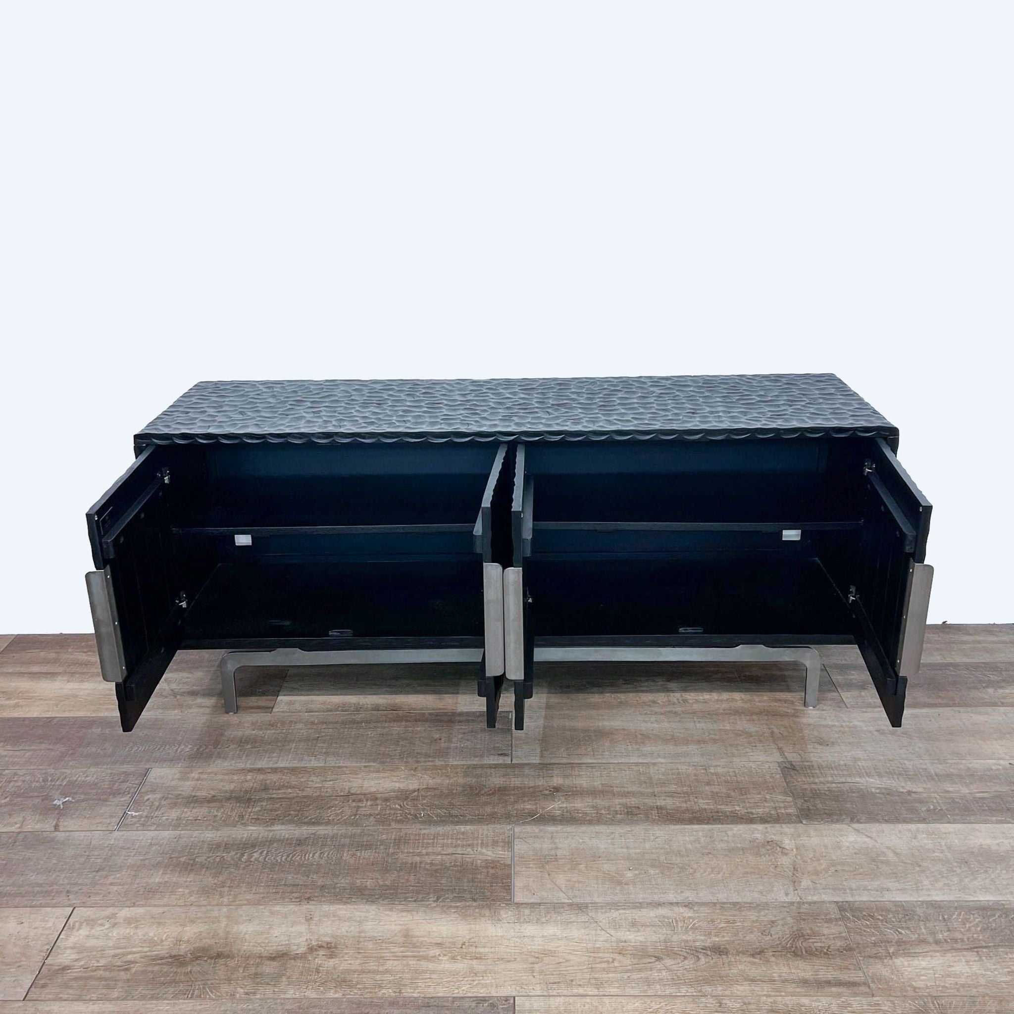 Alt text 2: Hand-carved black mango wood CB2 sideboard on a stainless steel base, open to show storage space and cord management holes.