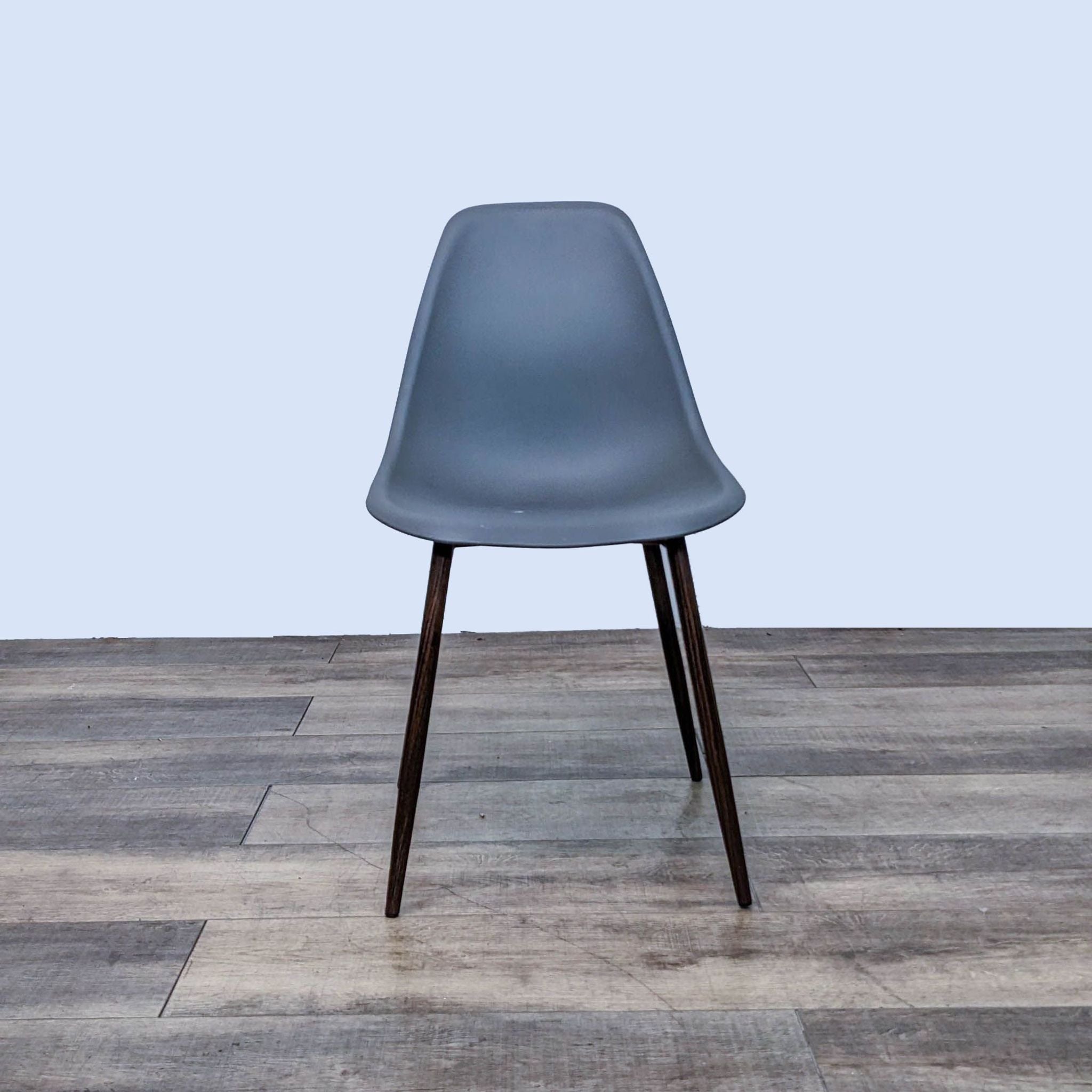 Reperch contemporary dining chair with gray sculpted plastic seat and wooden legs, shown from the front on wood flooring.