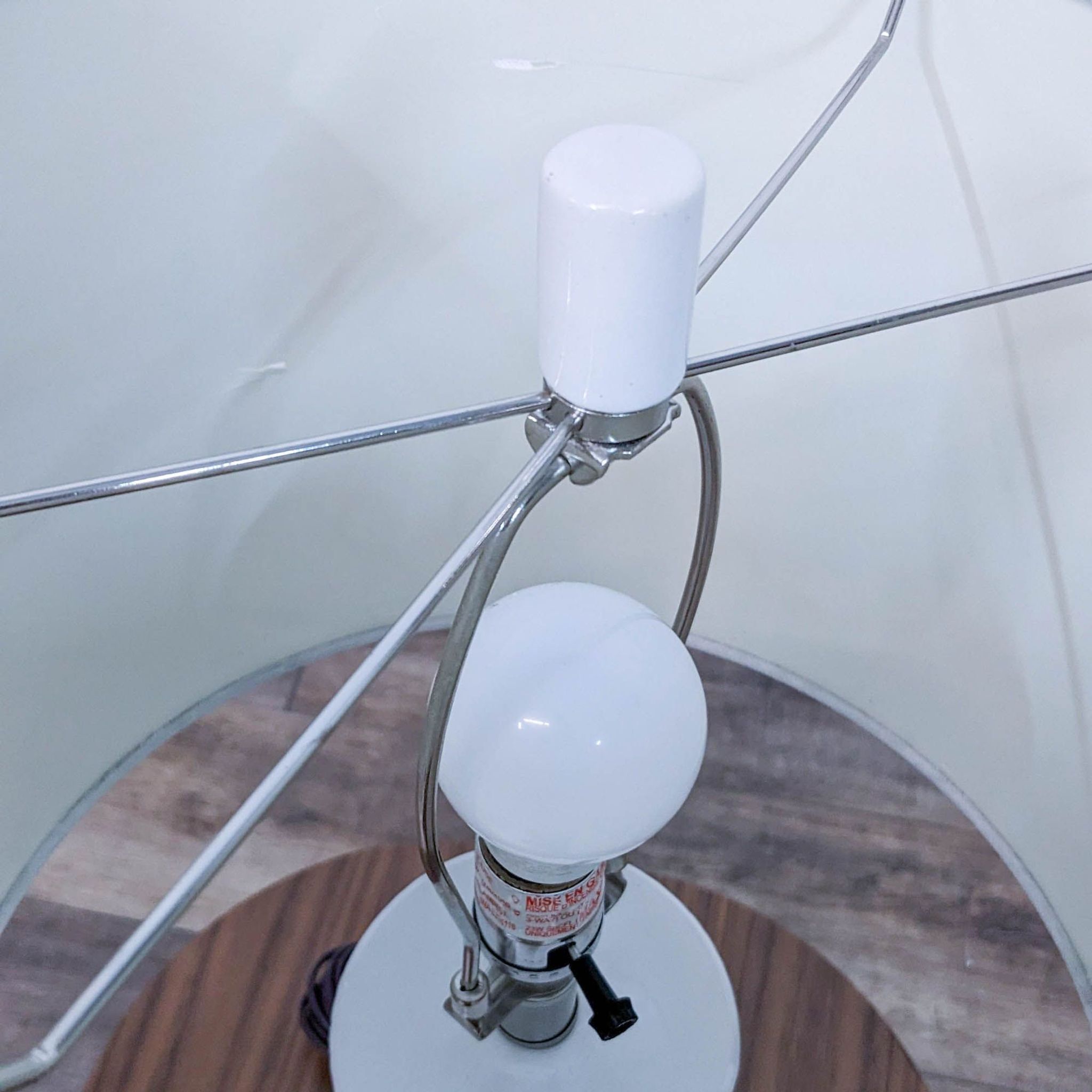 Modern Reperch desk lamp with a curved metal frame supporting a white round bulb, on a clear glass surface.