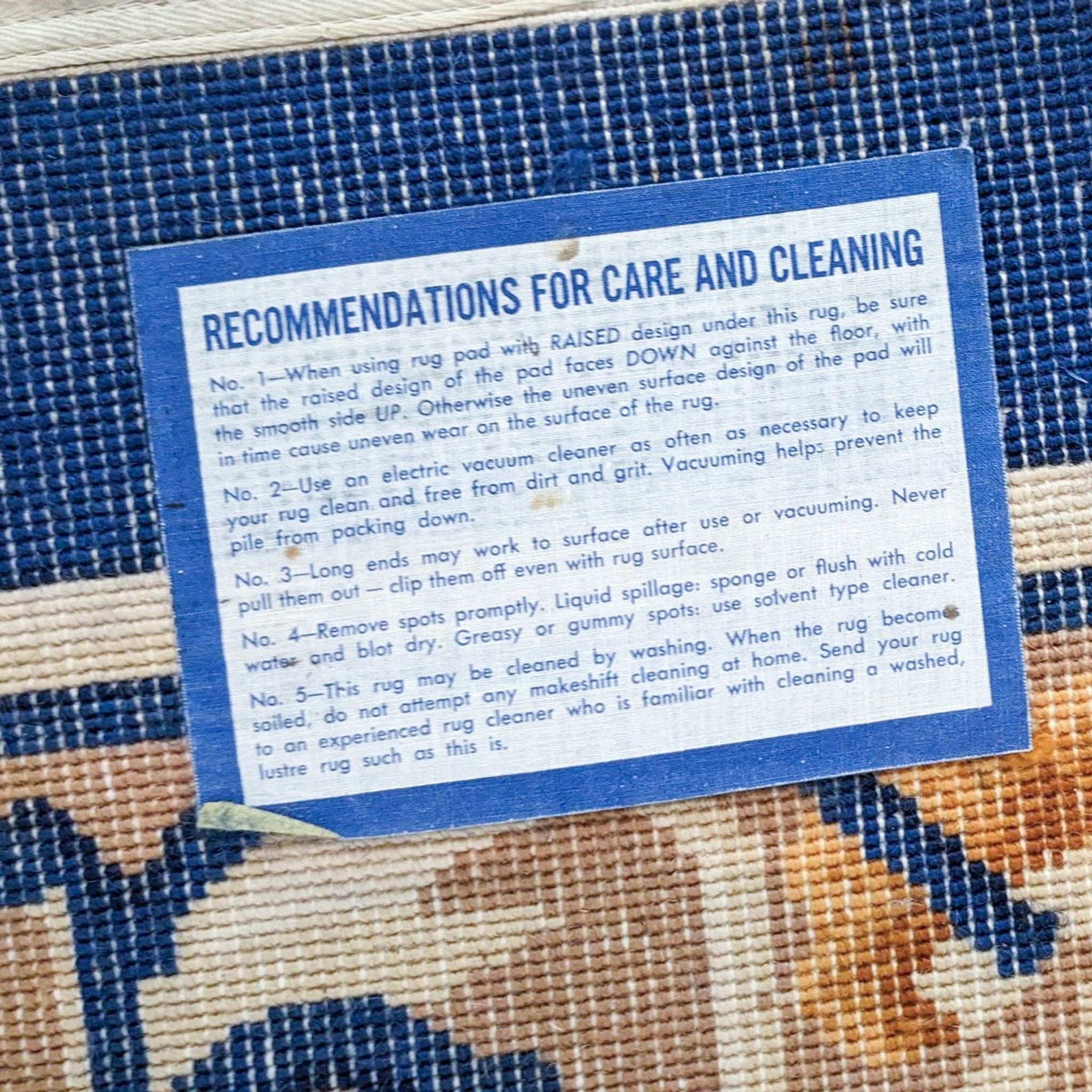 Alt text: Care instructions label on a Karastan wool area rug with details on cleaning and maintenance, set against a blue-and-cream patterned background.