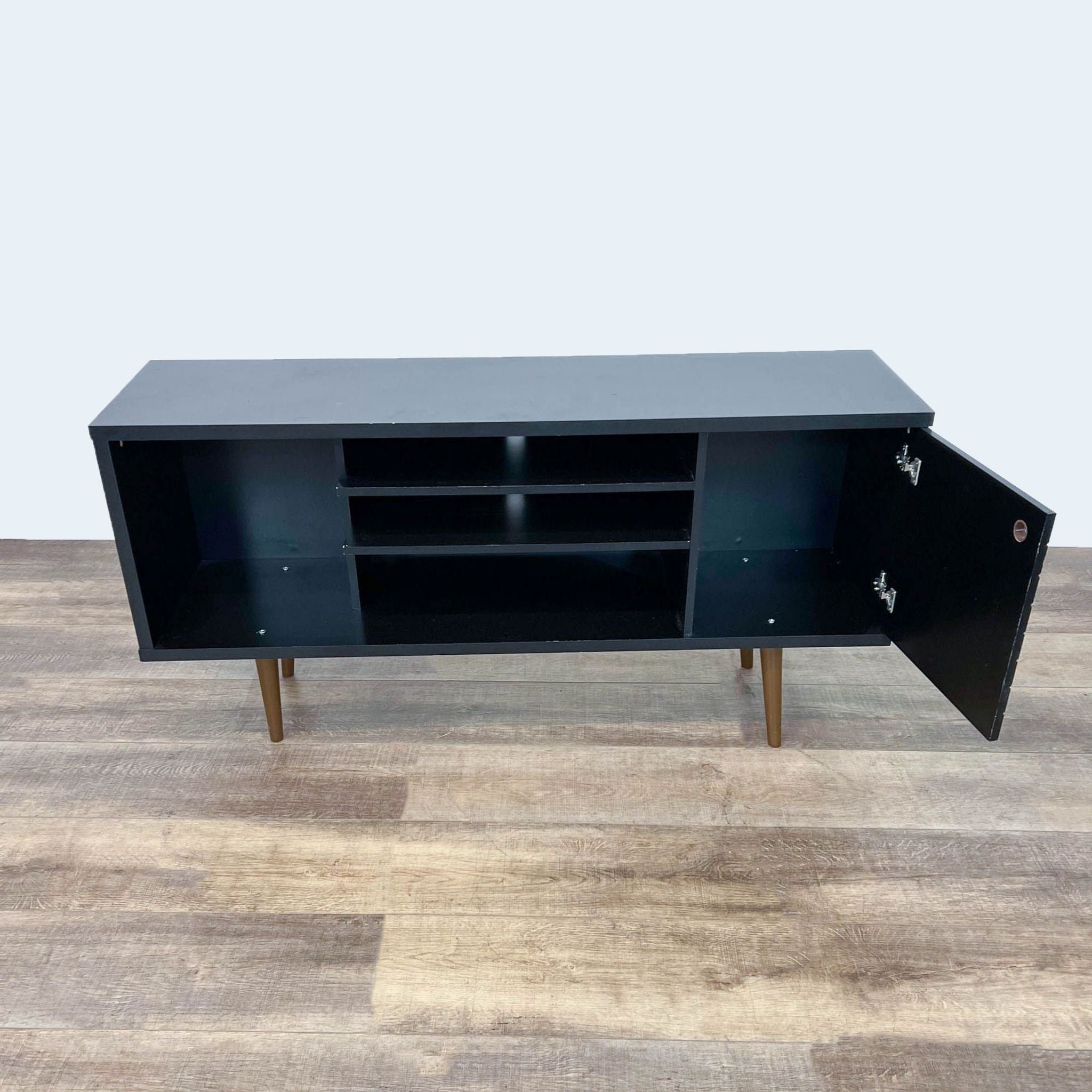 Reperch Entertainment Center with open compartments and door ajar, showcasing interior shelves, on a wood floor.