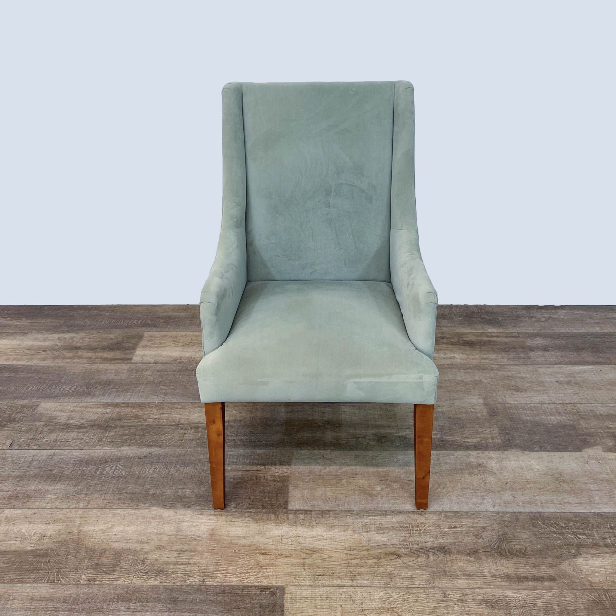 Contemporary World Market side chair with sloped arms, soft fabric upholstery, and tapered wooden legs, shown from the front.