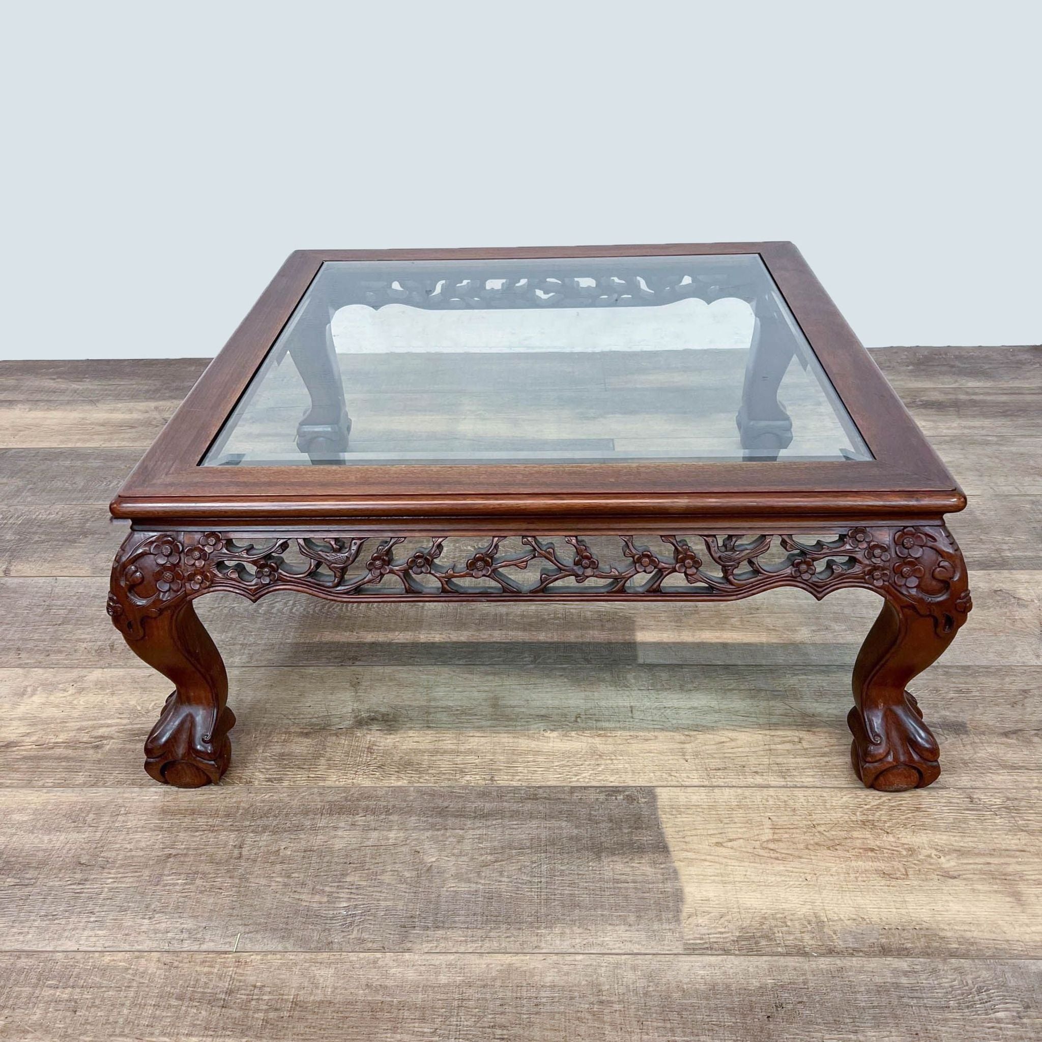 Elegant Reperch Chinese Chippendale coffee table with intricate woodwork and ball and claw feet, glass inset.