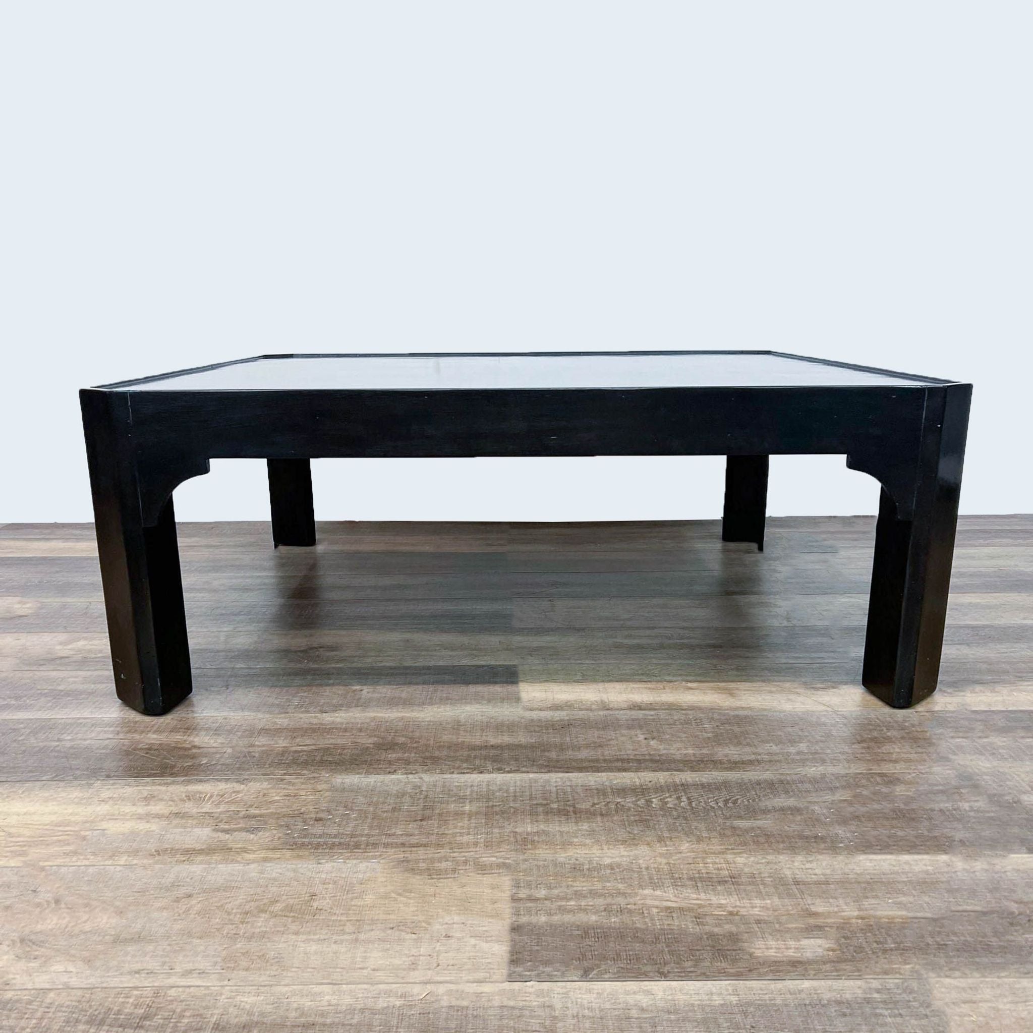 Black Dennis & Leen coffee table with straight legs and square top on a wooden floor.