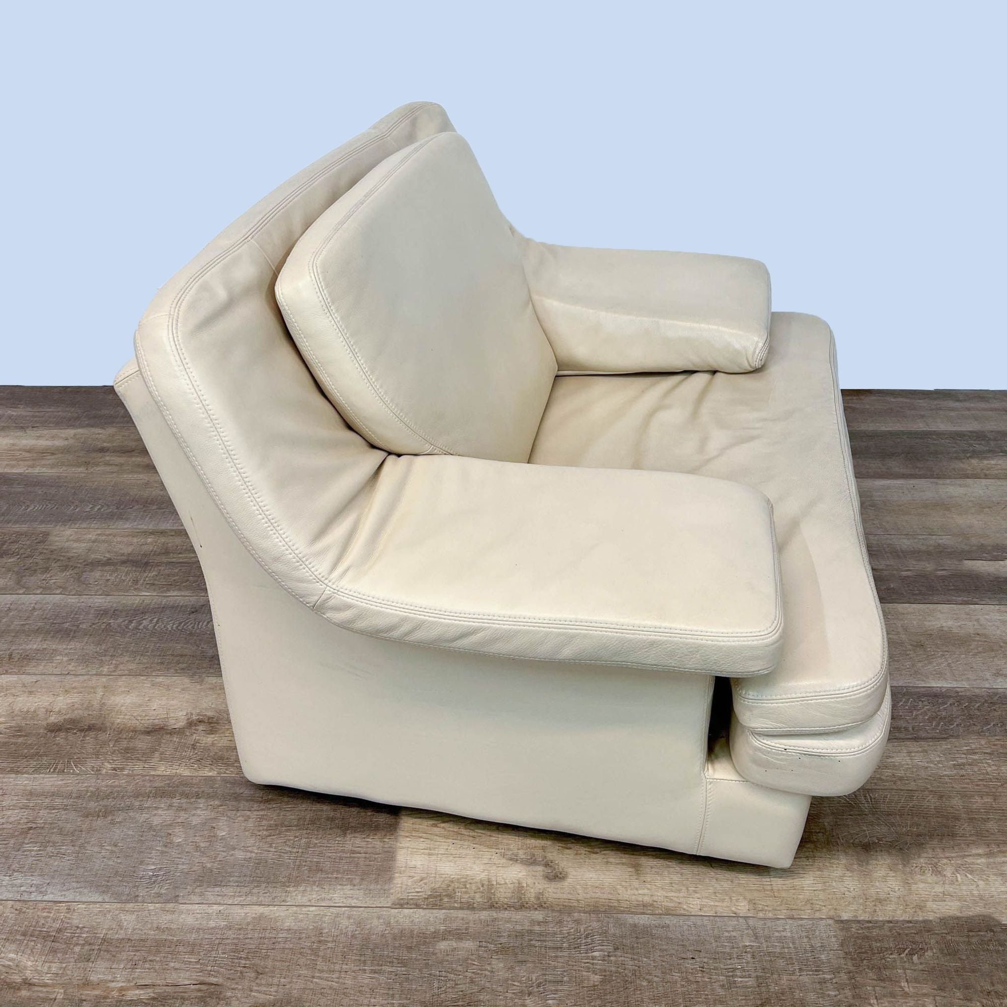 Reperch modern lounge chair in cream leather with plush upholstery and broad armrests on wood feet. Angled and rear views.