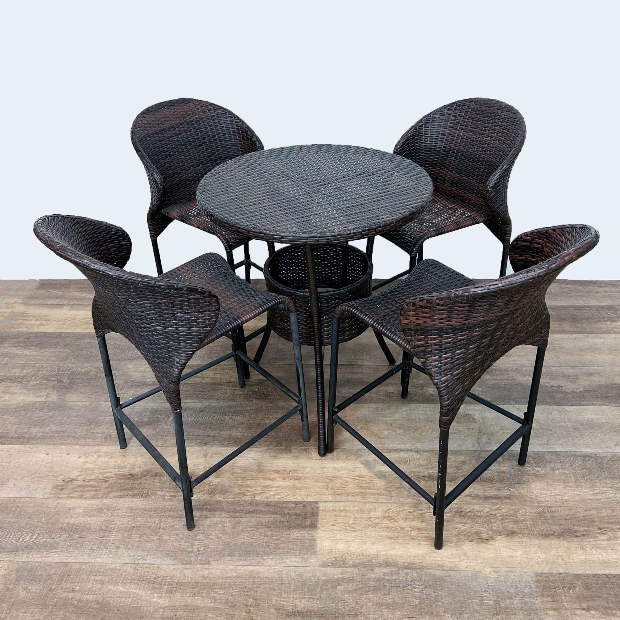 Reperch brand small round resin wicker table with four matching chairs on metal frames, set on a wooden floor.