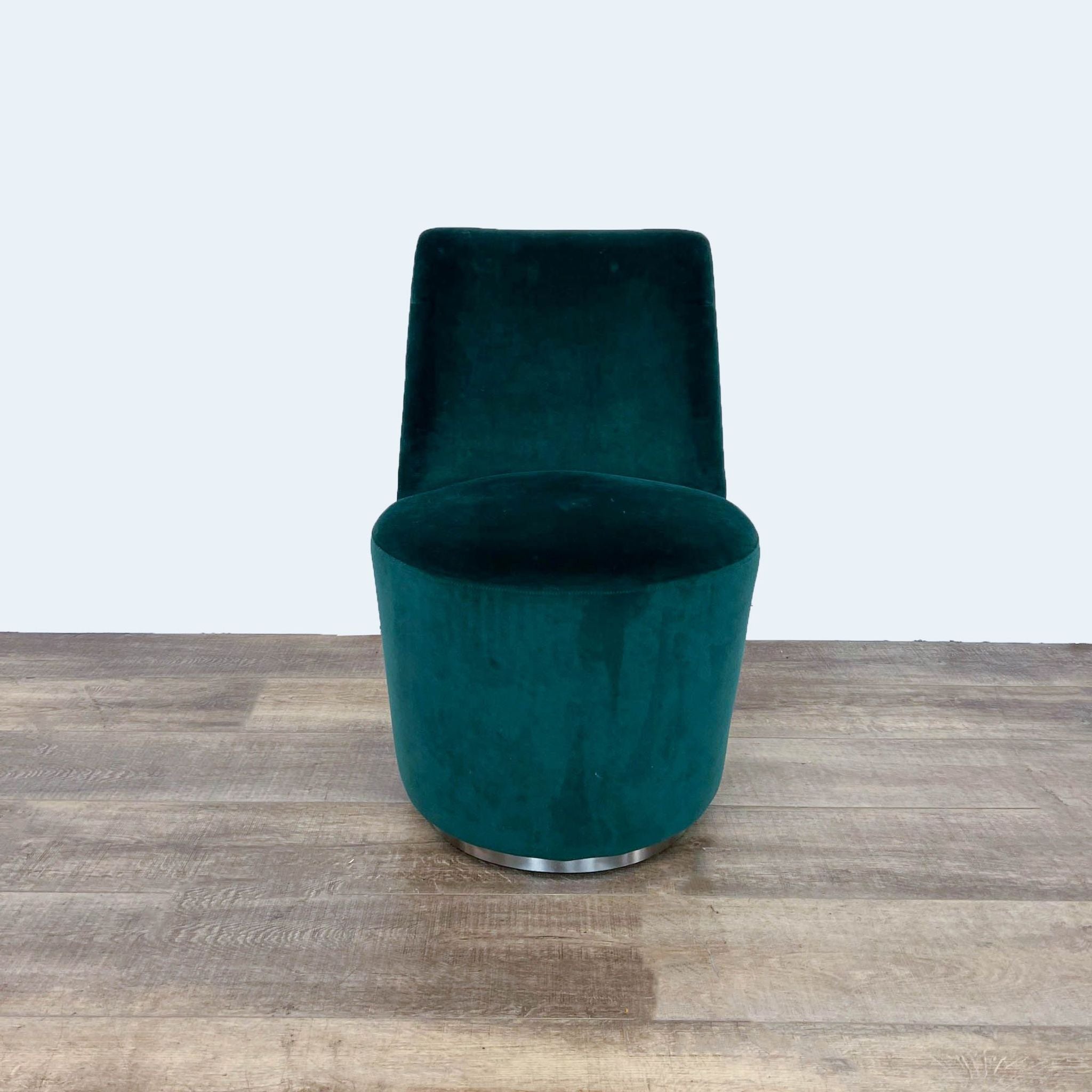 Hunter green Crate & Barrel Ofelia dining chair with velvet upholstery and swivel base on a wood floor.