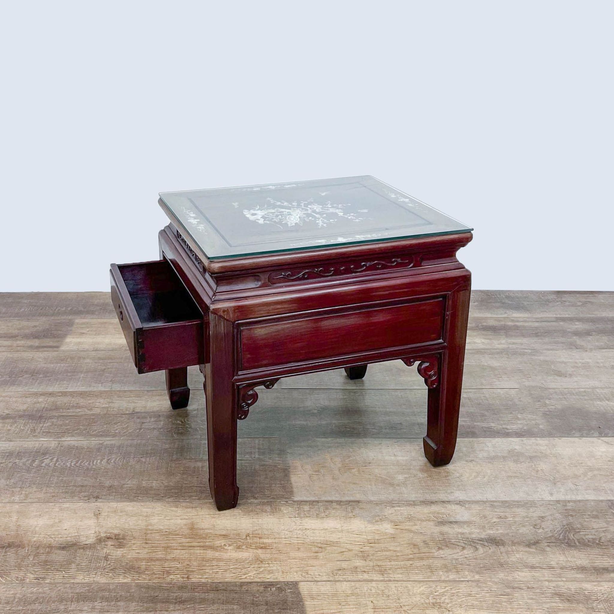 Wooden end table by Reperch with glass top revealing Mother of Pearl inlay, shown with a pull-out drawer extended.