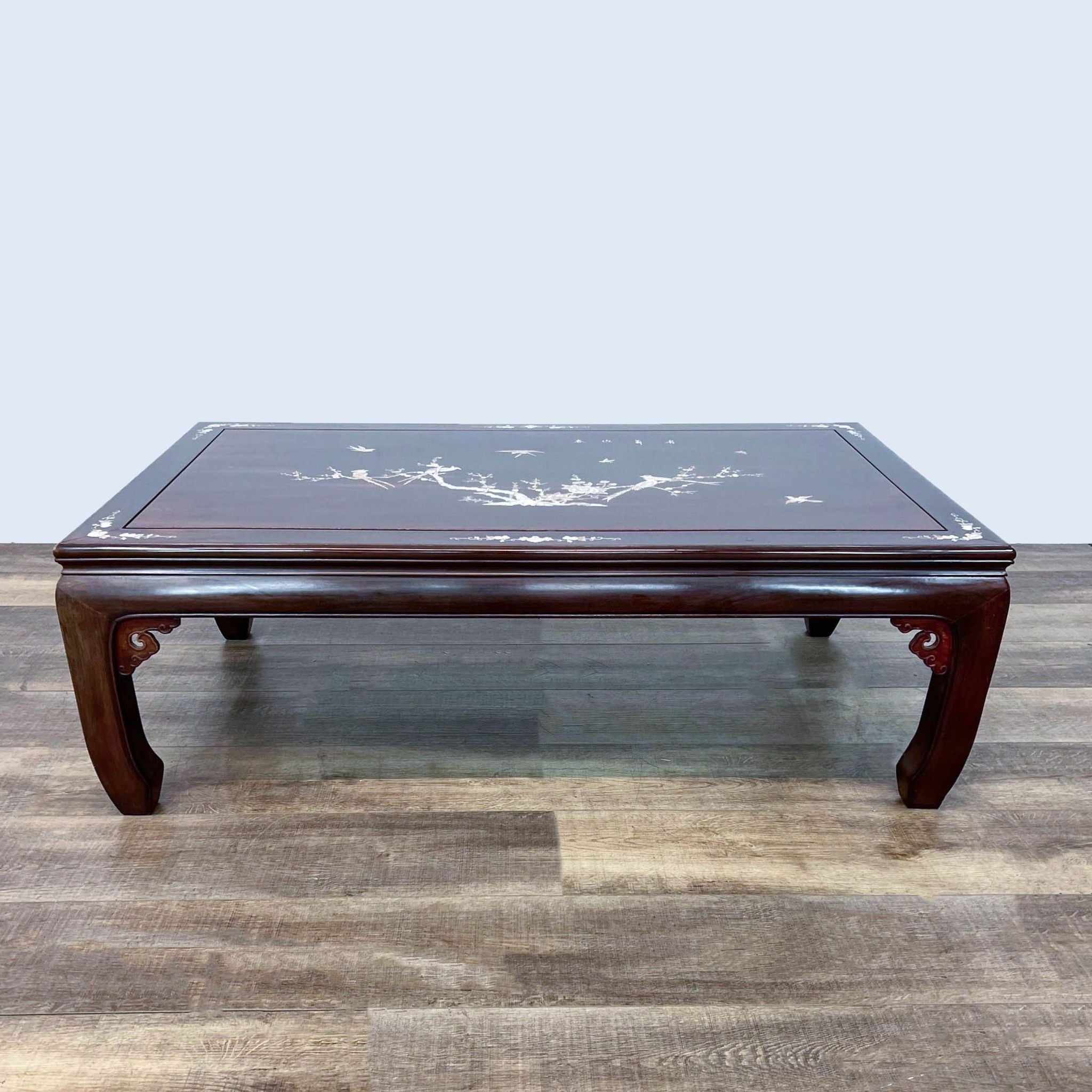 Reperch coffee table with elegant mother of pearl inlay on dark wood, set against a grey background.