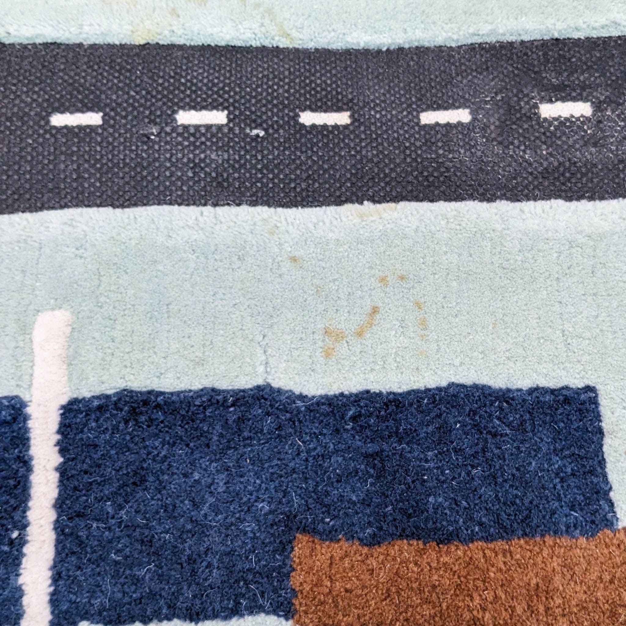 Alt text: Close-up of City Car Kids Area Rug by Crate & Barrel showing detailed road and grass textures with slight stain.