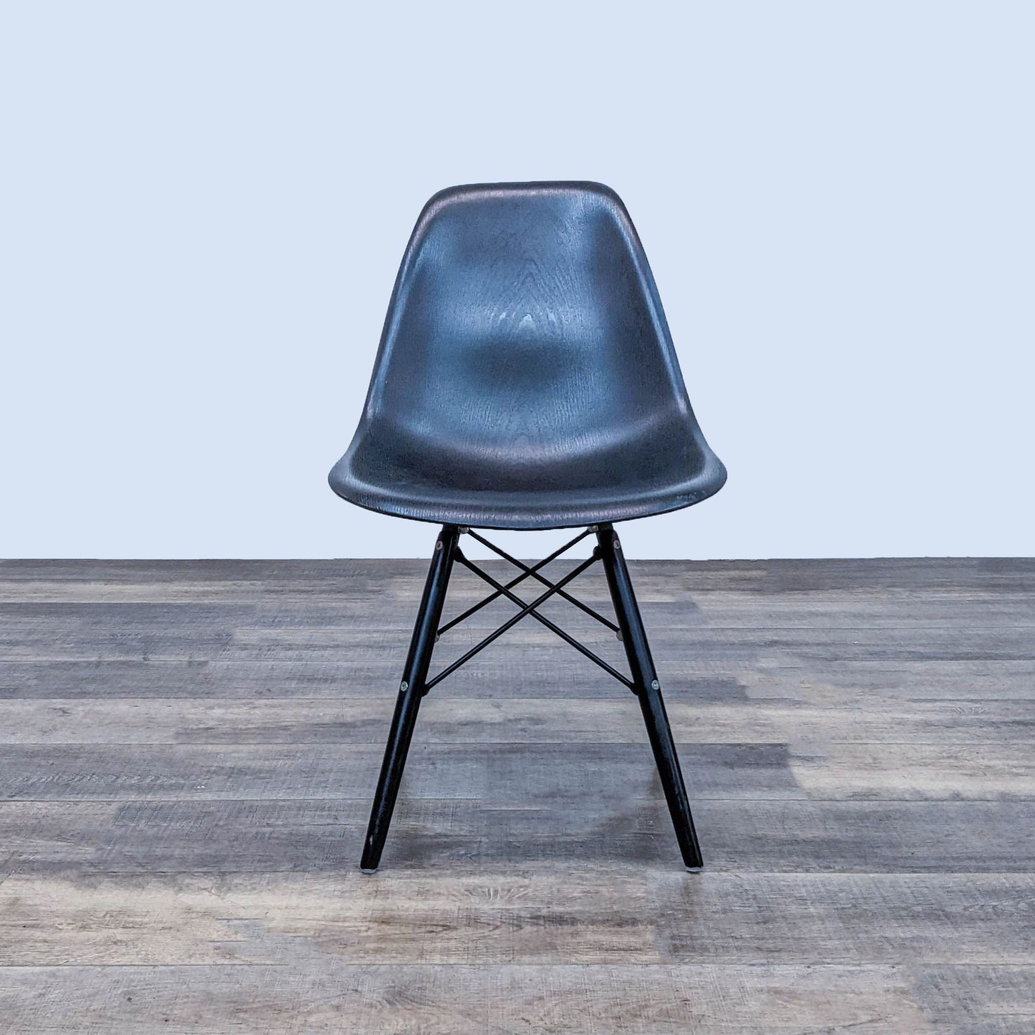 Reperch contoured black plastic dining chair with wood grain texture on Eiffel-style metal base, frontal view.