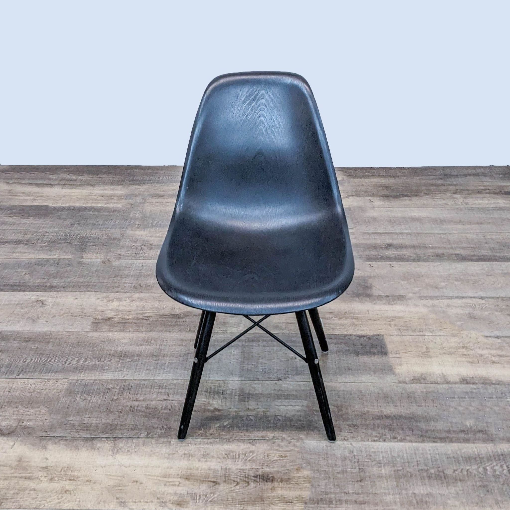 Reperch dining chair with a black contoured moulded seat and a black metal Eiffel style base on a wooden floor.
