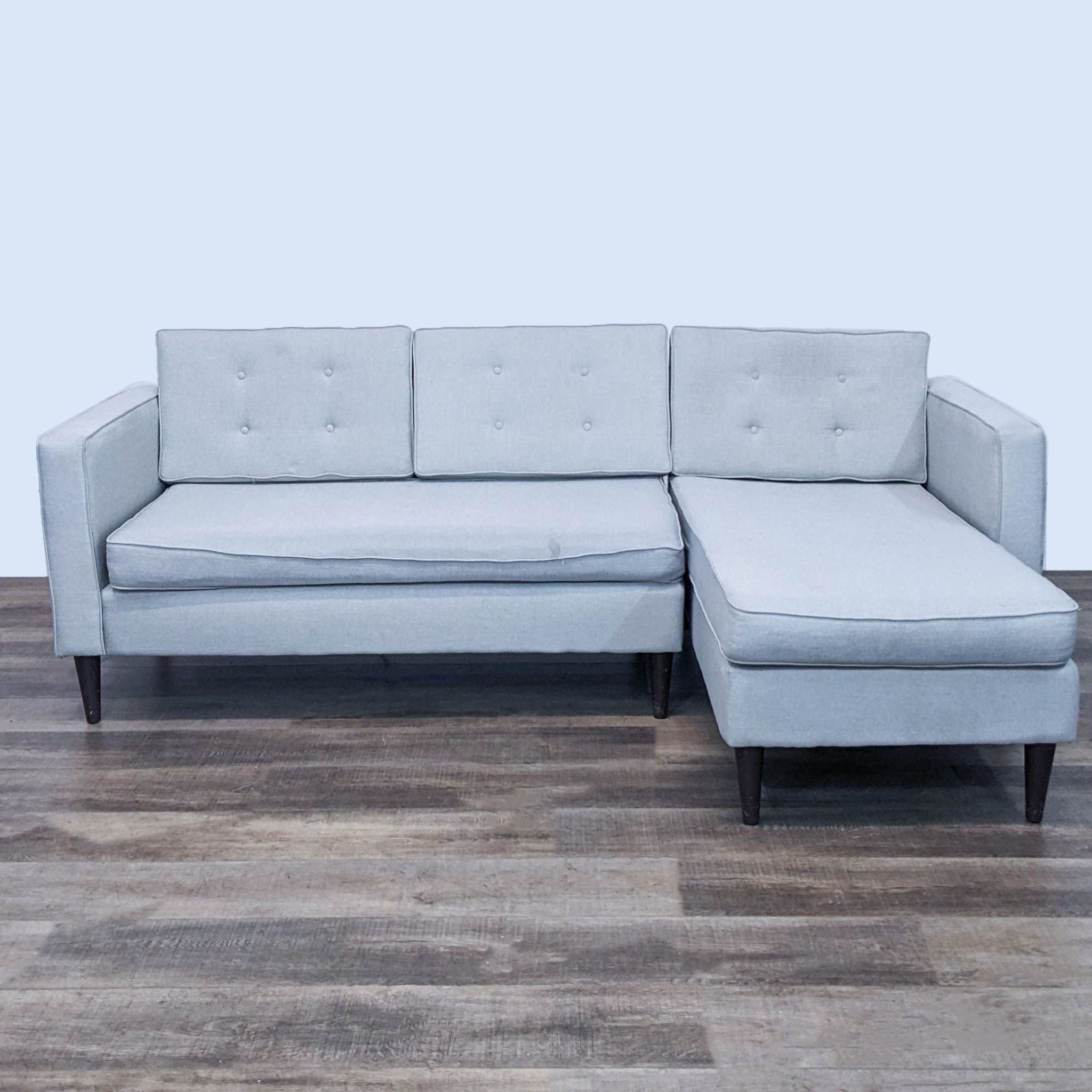 Reperch brand two-piece sectional sofa with tufted back, narrow arms, and tapered legs on a wooden floor.